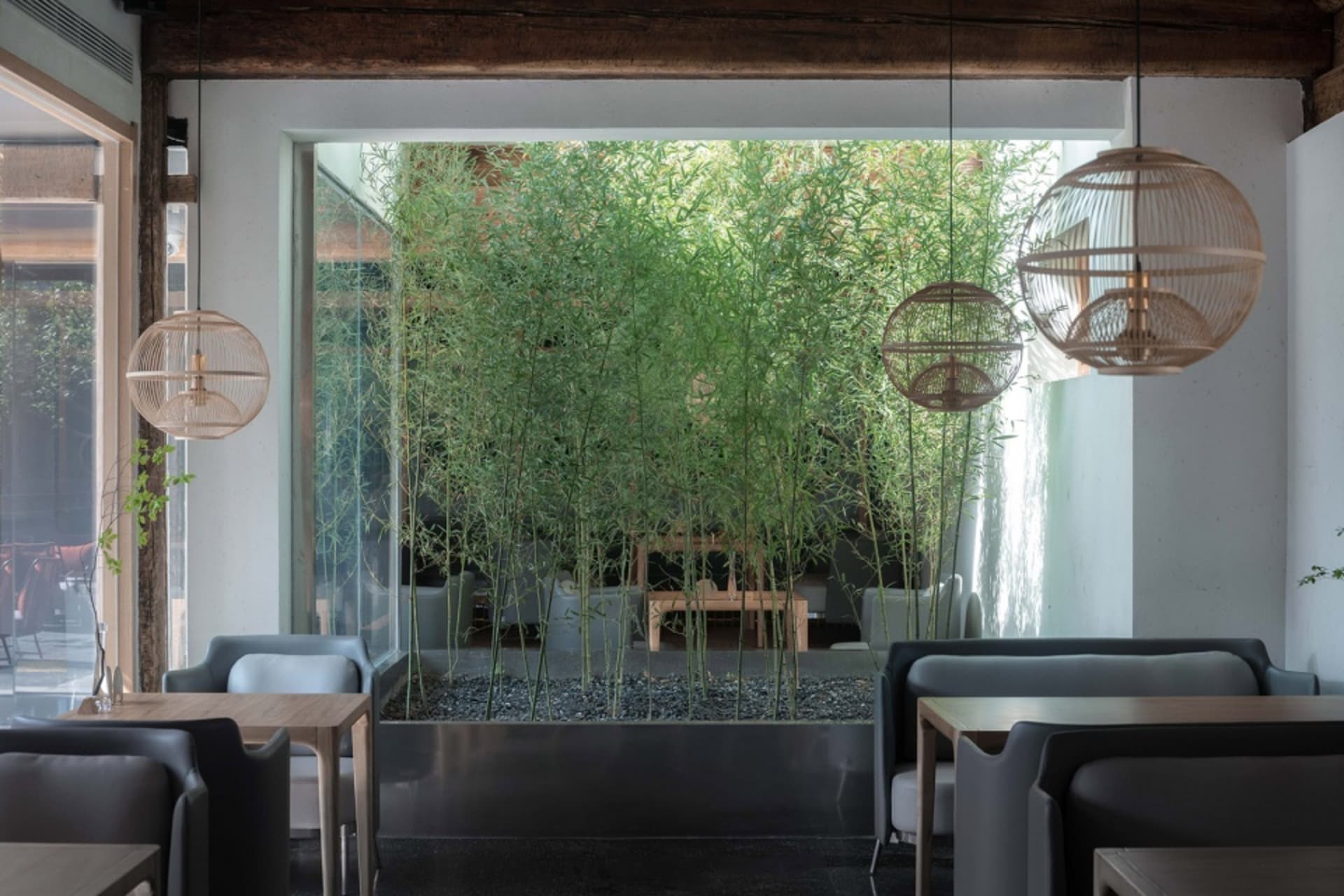 A modern coffee shop with wooden tables, glass walls, and metal accents.