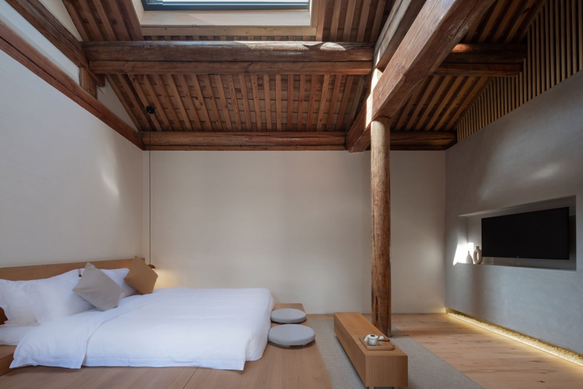 A contemporary bedroom featuring concrete walls, wooden floor and furniture, and a minimalist design.