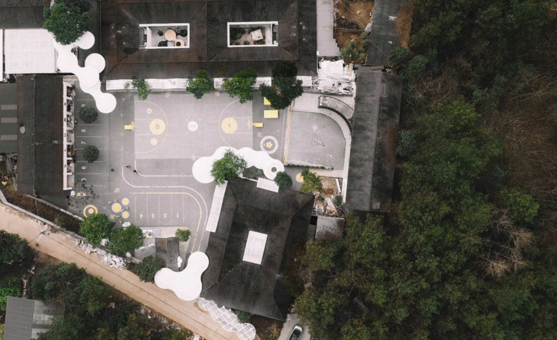 Aerial view of a modern school ground plan with concrete and asphalt surfaces and artificial trees.