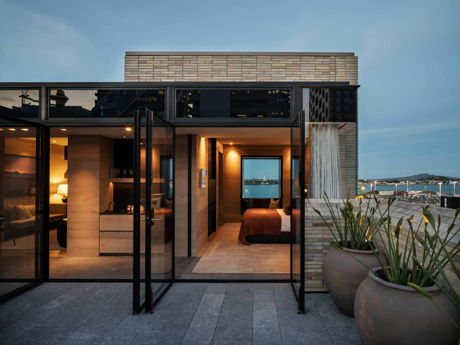 Modern rooftop deck featuring brick and glass materials, overlooking a scenic body of water.