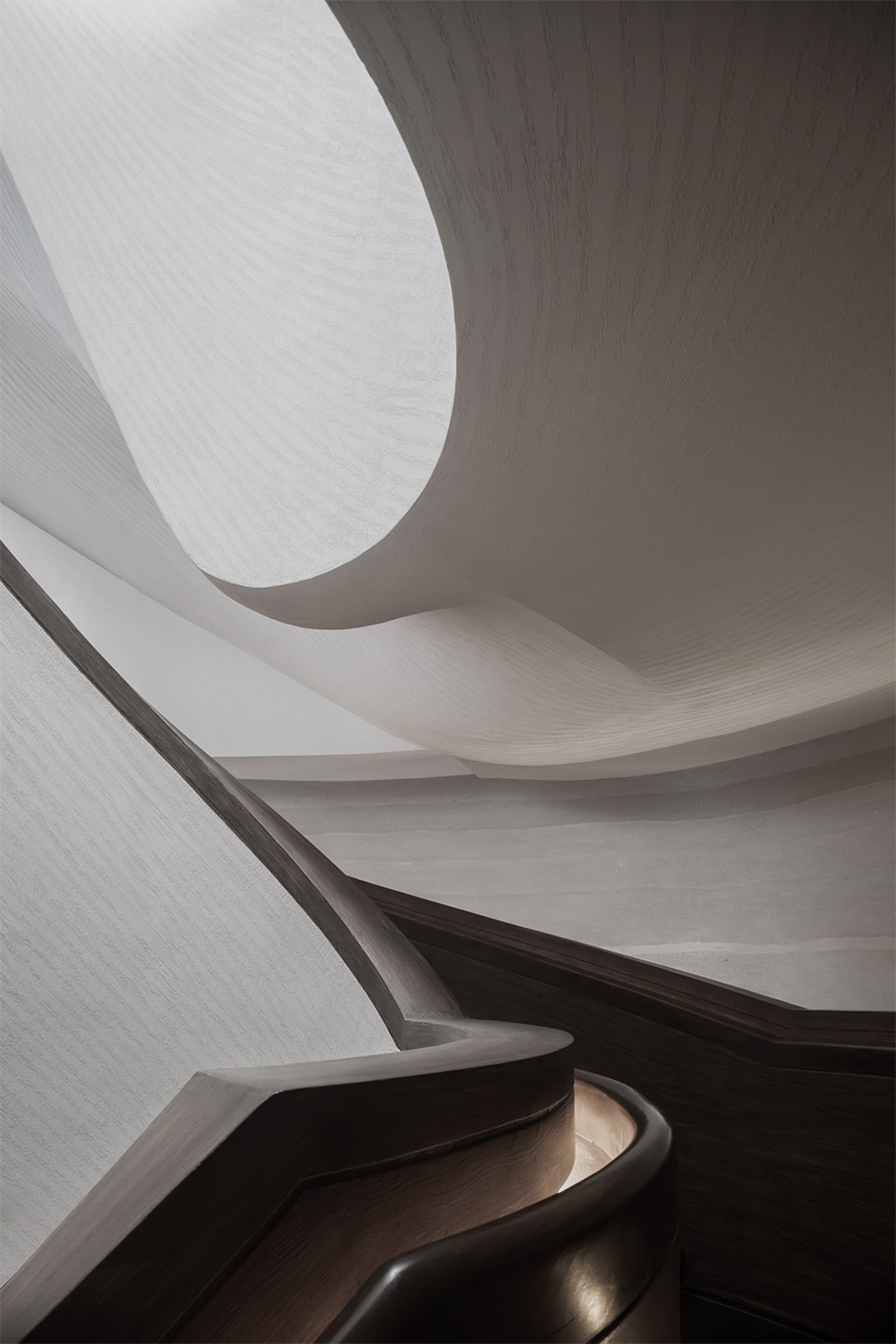 A modern staircase with wooden railings and a curved design.