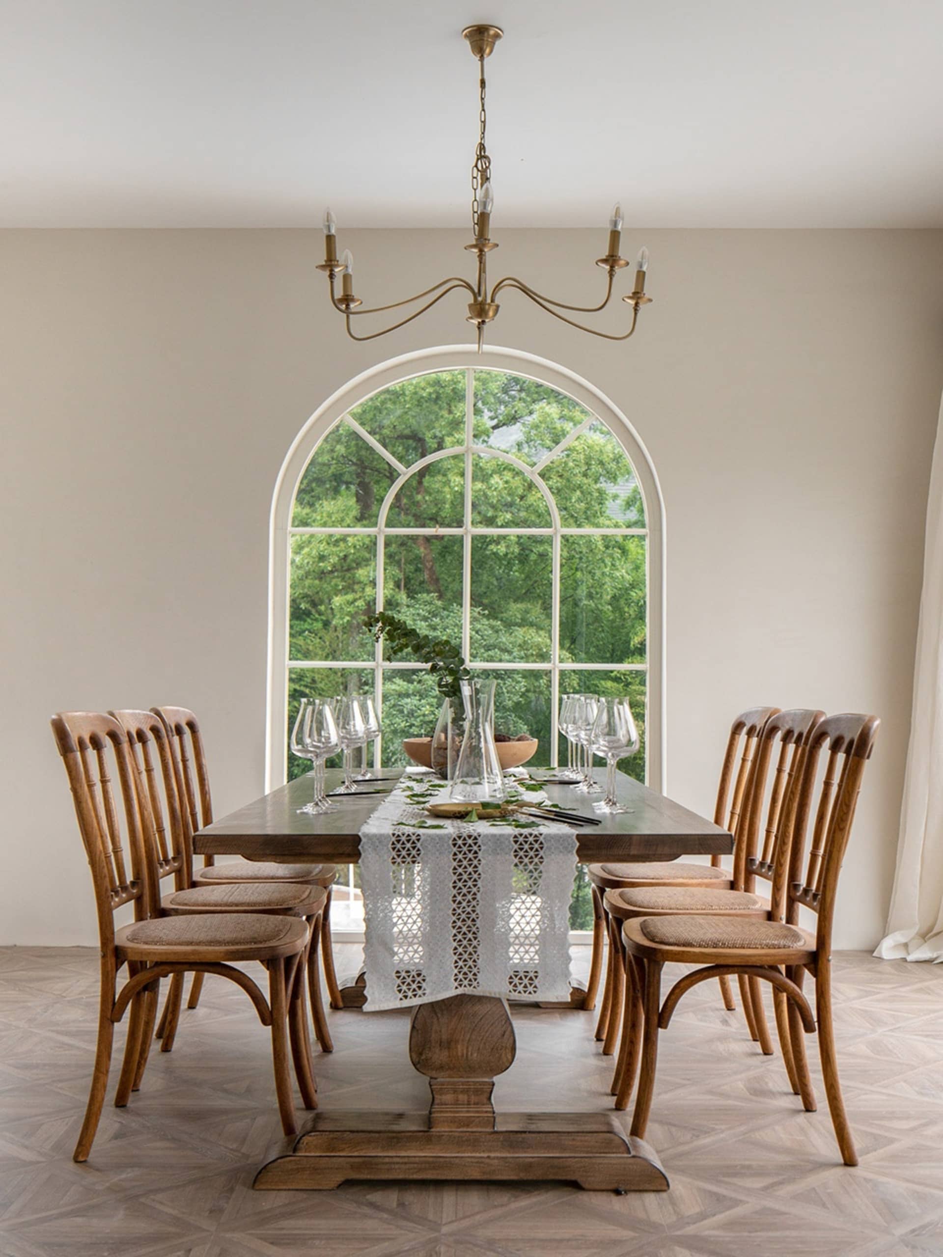 A modern dining room with a wooden table, glass vases, and fabric chairs.