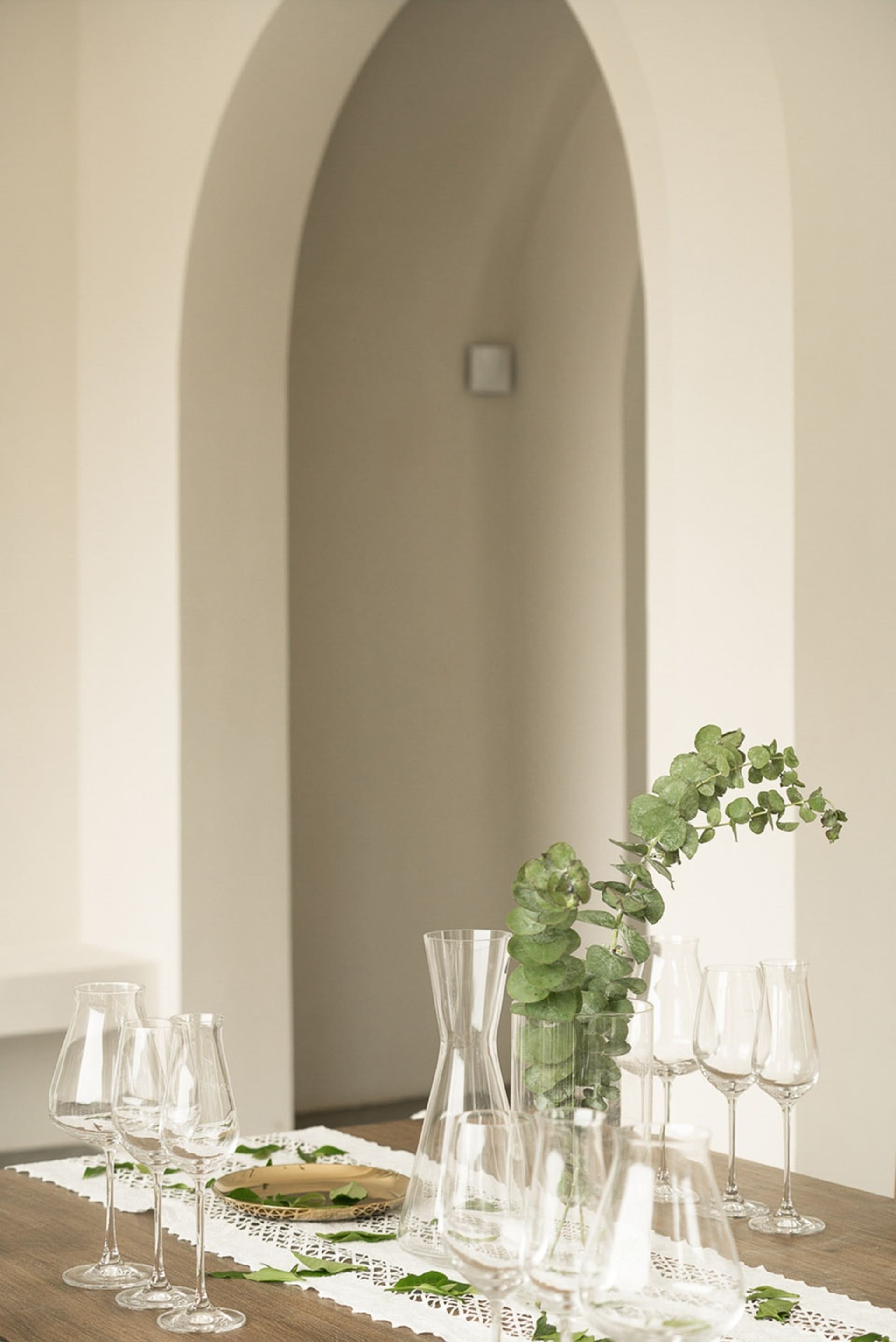 A pristine dining table with modern glassware and greenery.