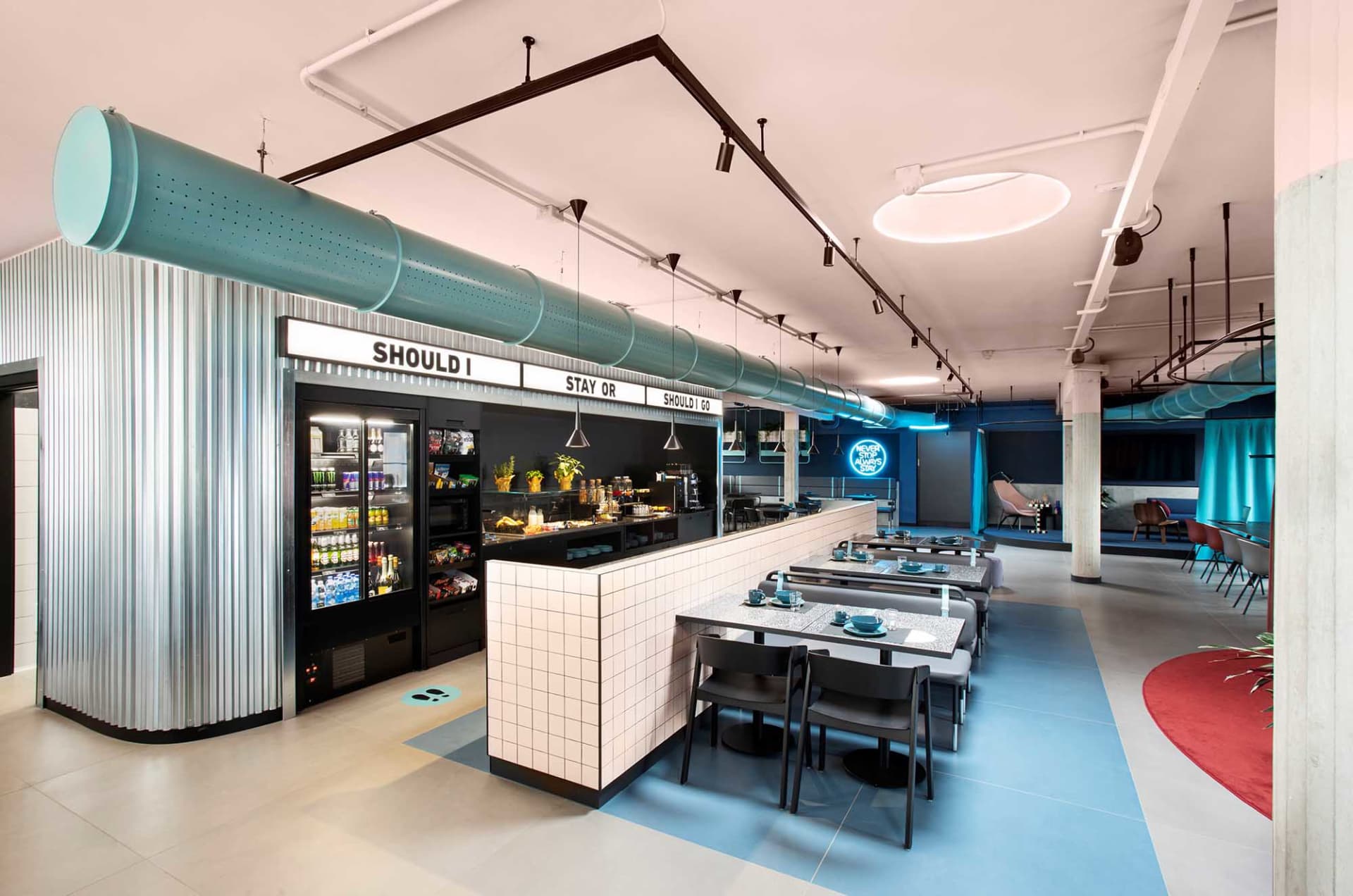 An industrial-style cafe with metal pipes, glass surfaces, and concrete flooring.