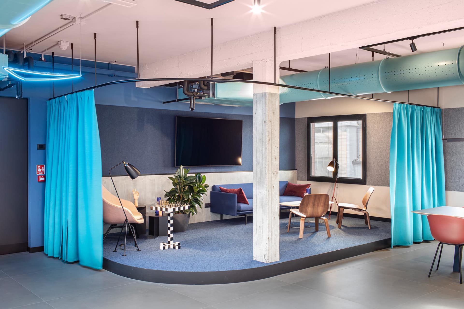 A modern industrial office lounge features concrete, glass, and fabric materials.