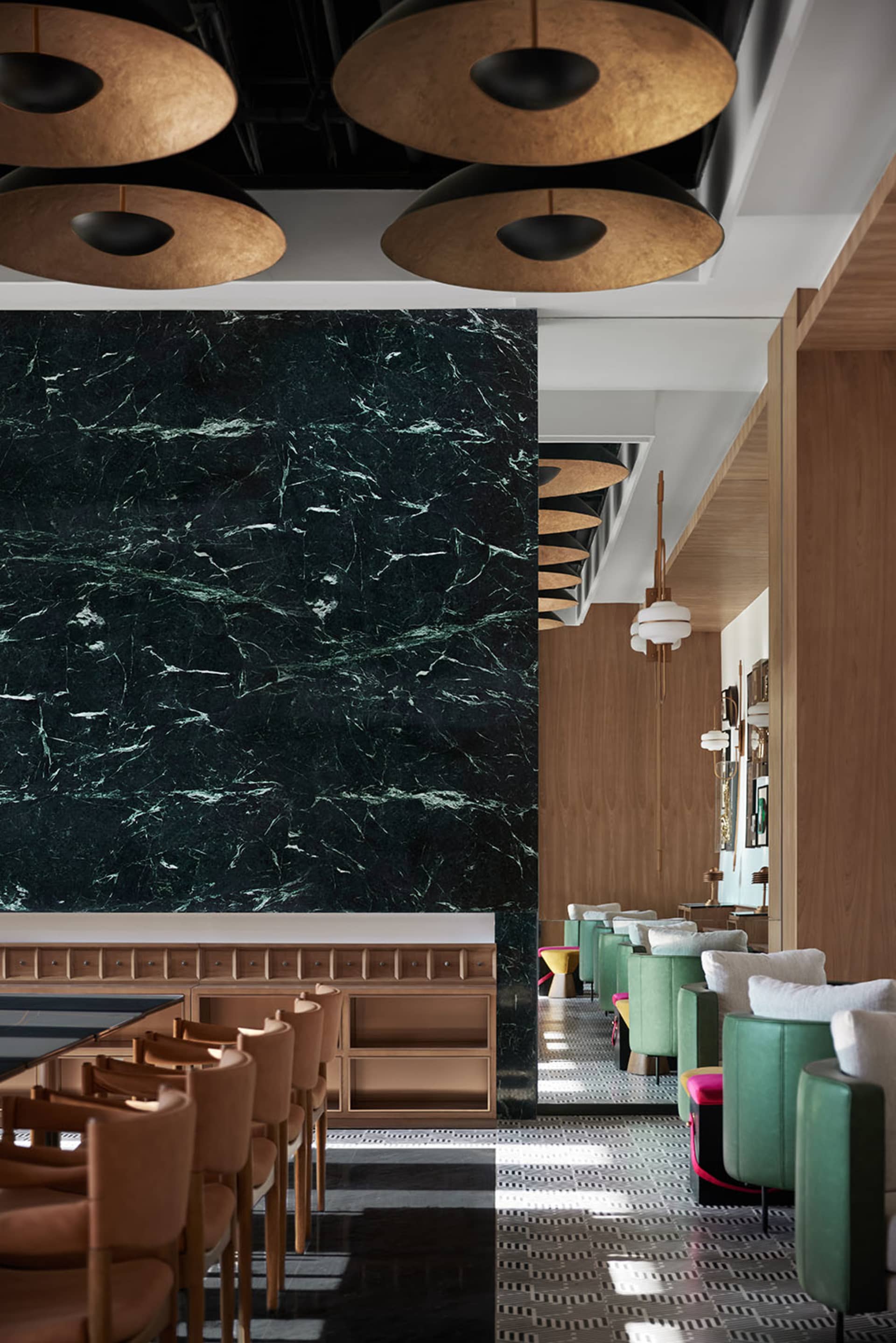Modern restaurant interior featuring a marble wall and wooden tables.
