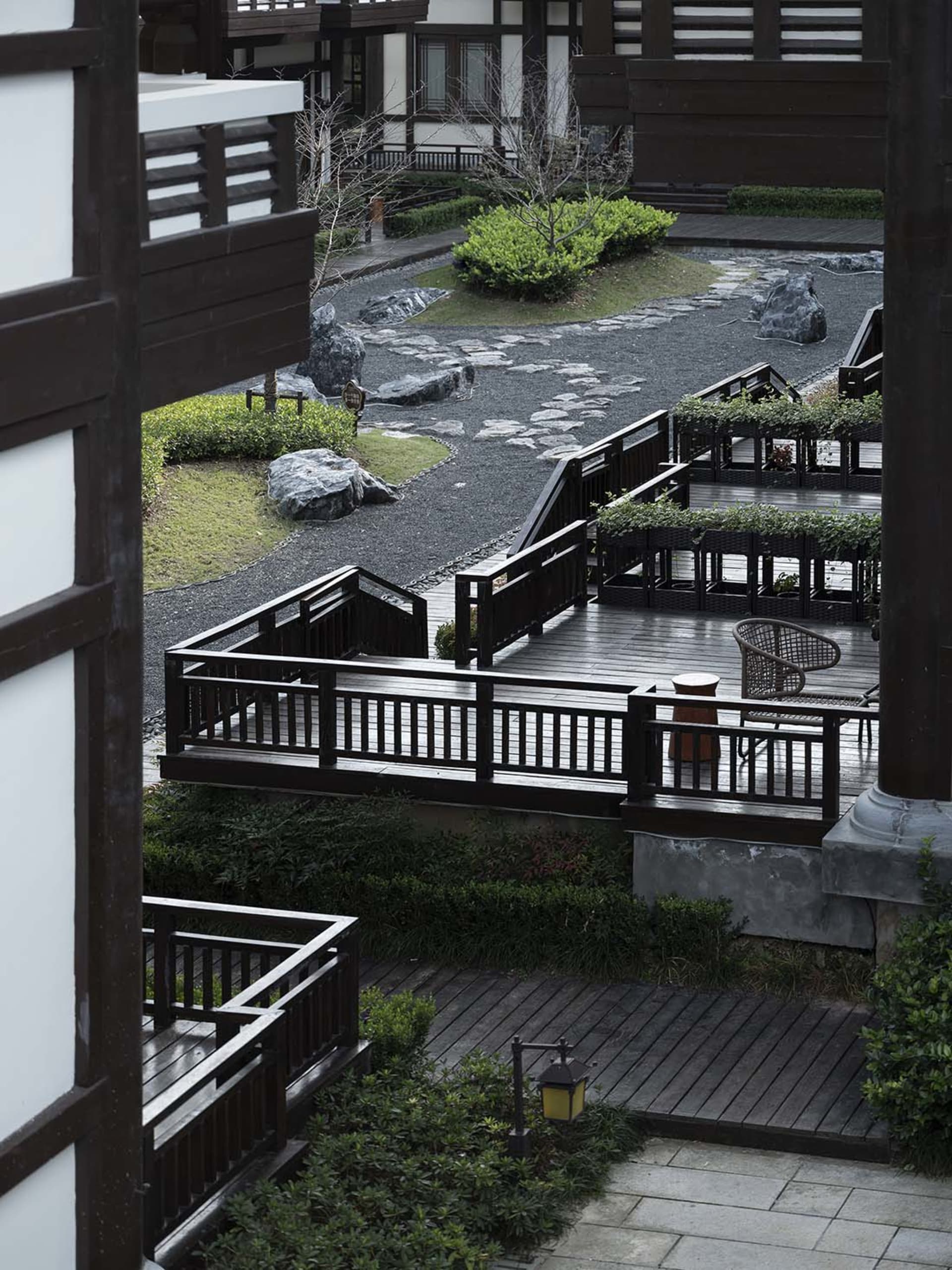 一座現代住宅花園,木質步道穿梭於綠意與岩石之間。