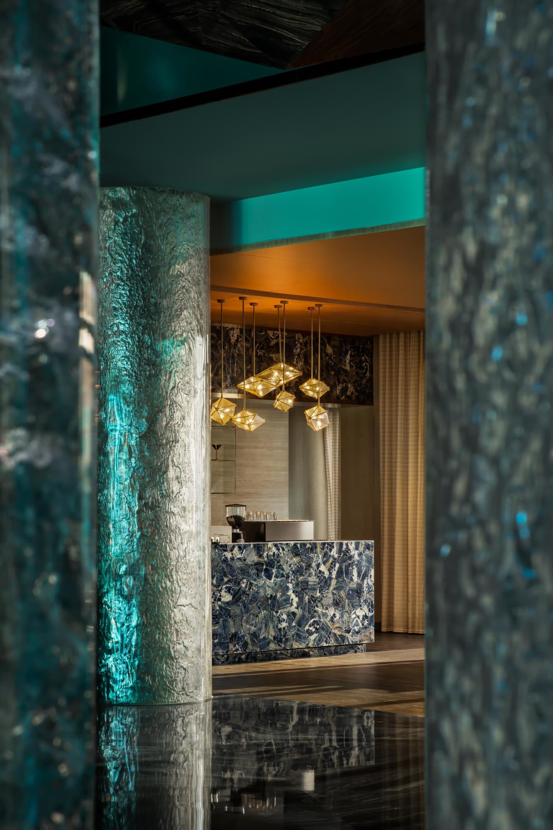 Modern hotel lobby with marble finishes and glass pendant lights.