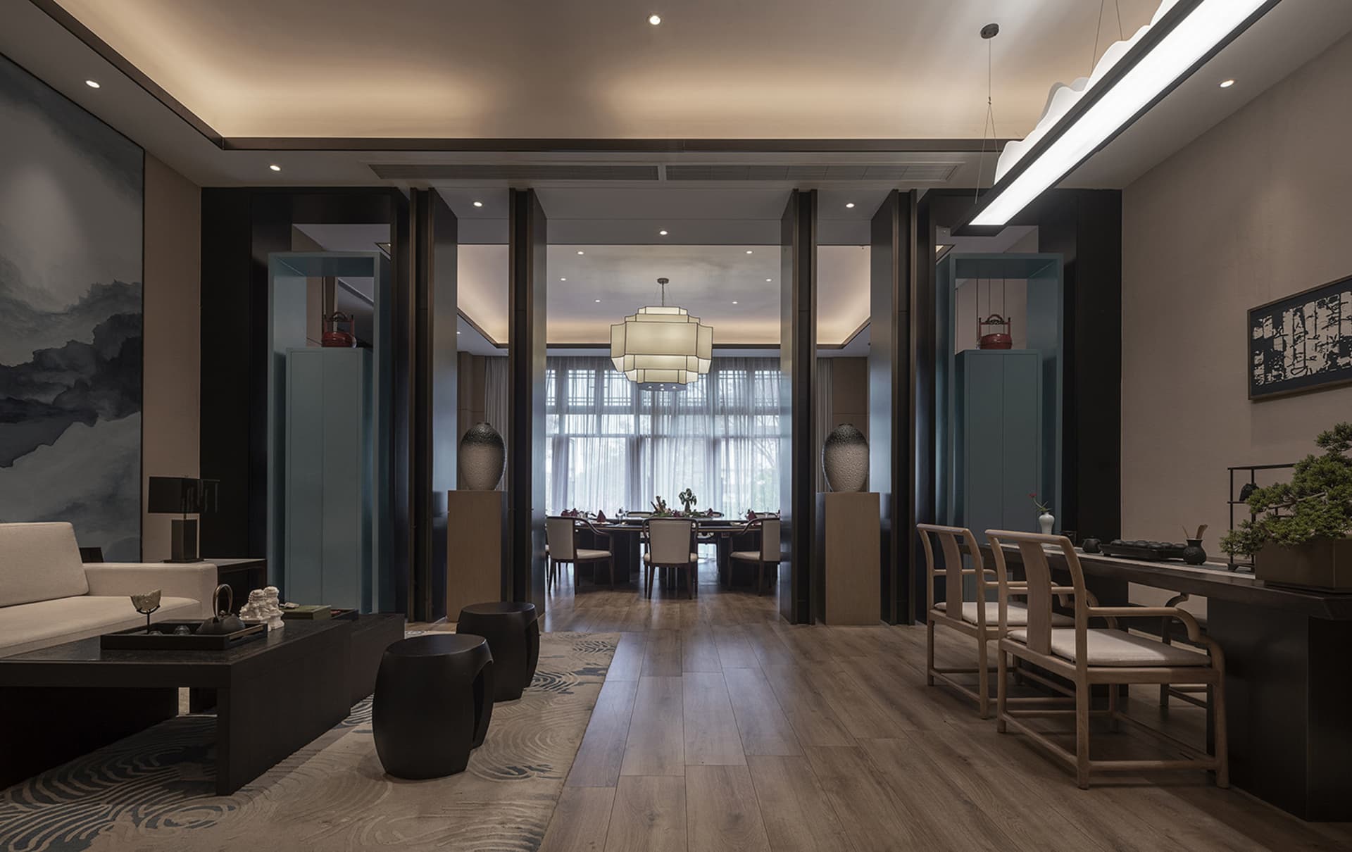 A modern living and dining room interior with wooden flooring, glass elements, and fabric seating.