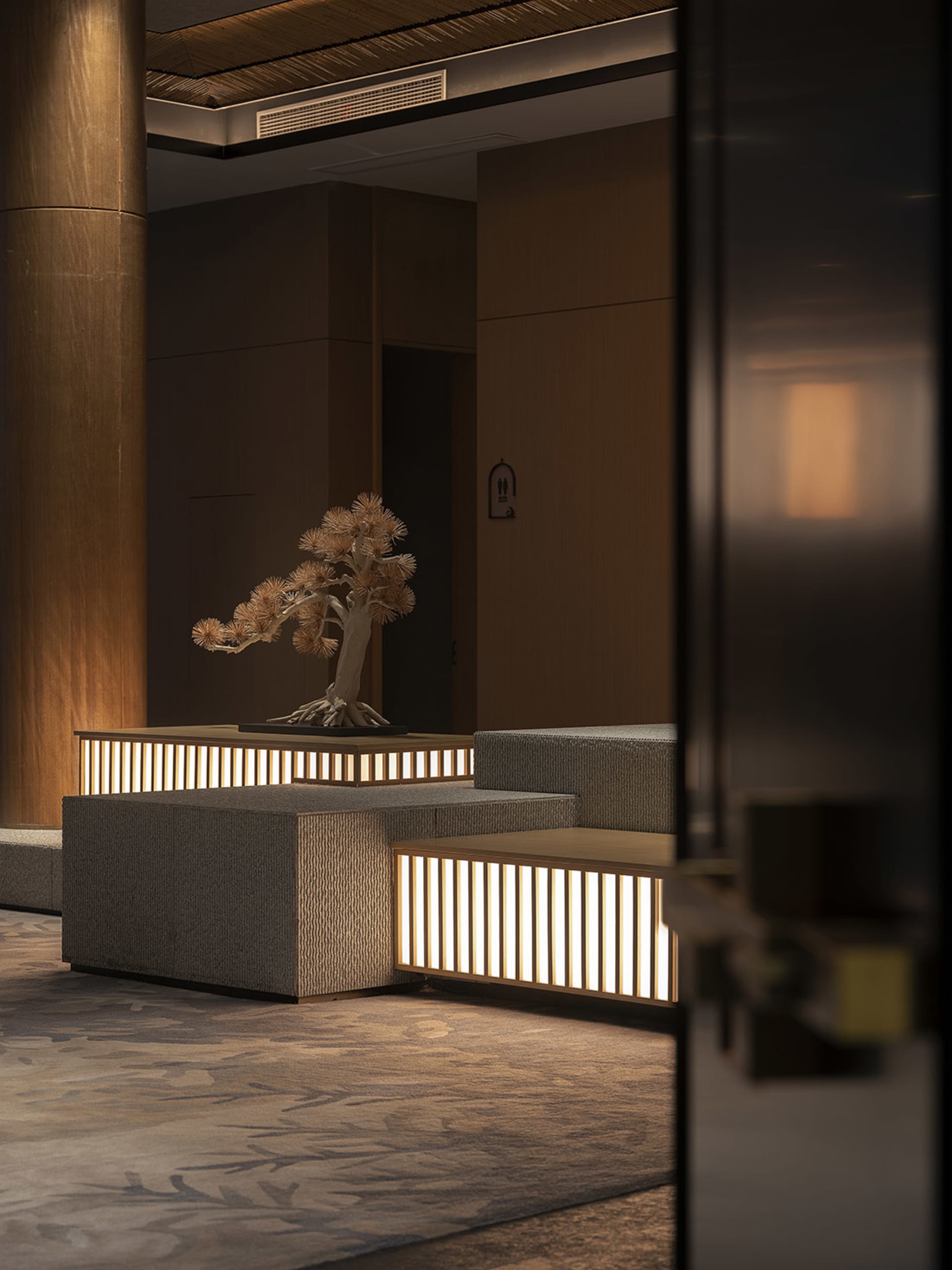 Modern lobby featuring concrete walls and natural lighting, illuminated by soft, ambient light, with a minimalist design and 