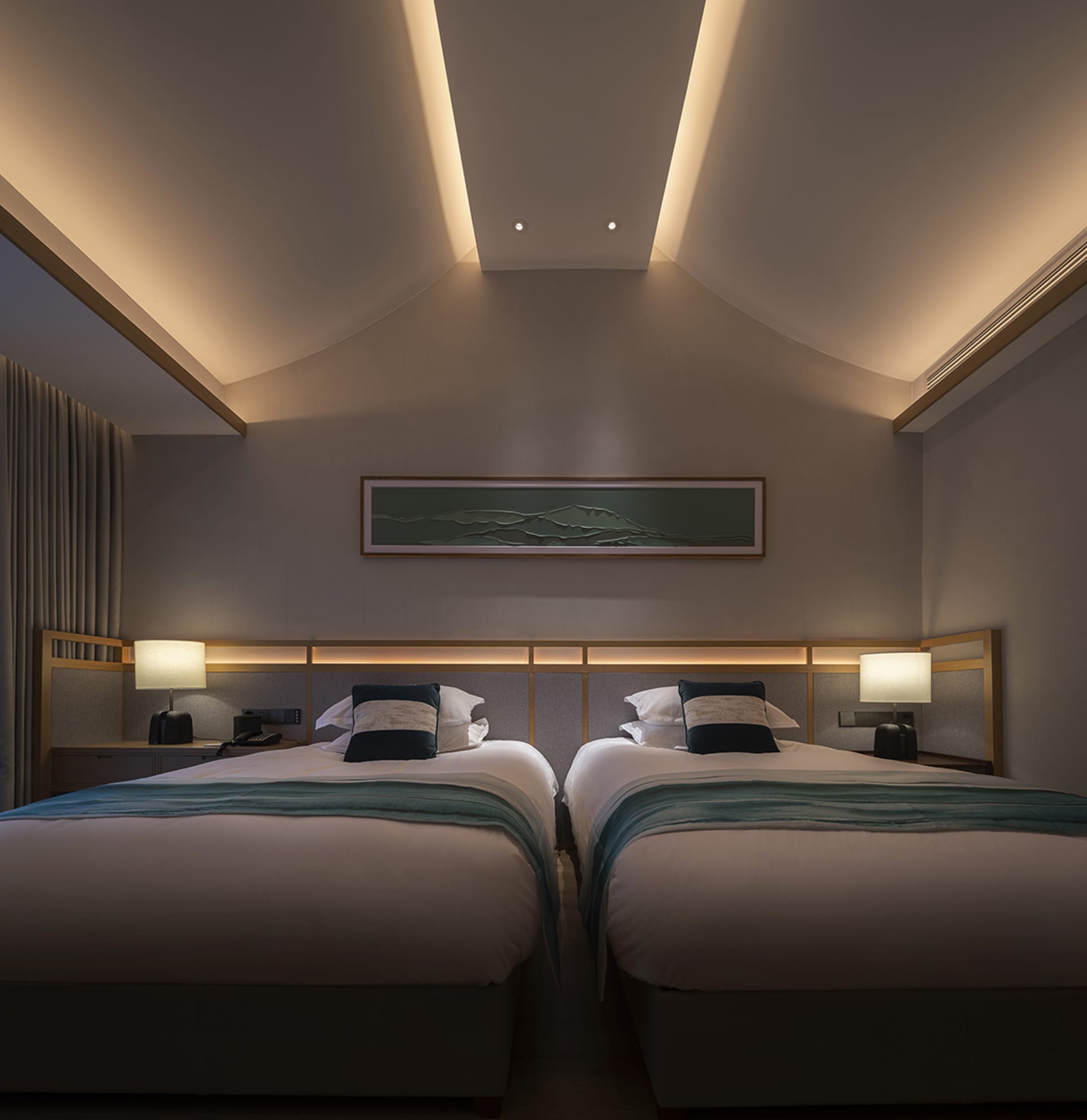 A modern minimalist bedroom featuring fabric and wood elements, with two twin beds, a headboard, and a light fixture.