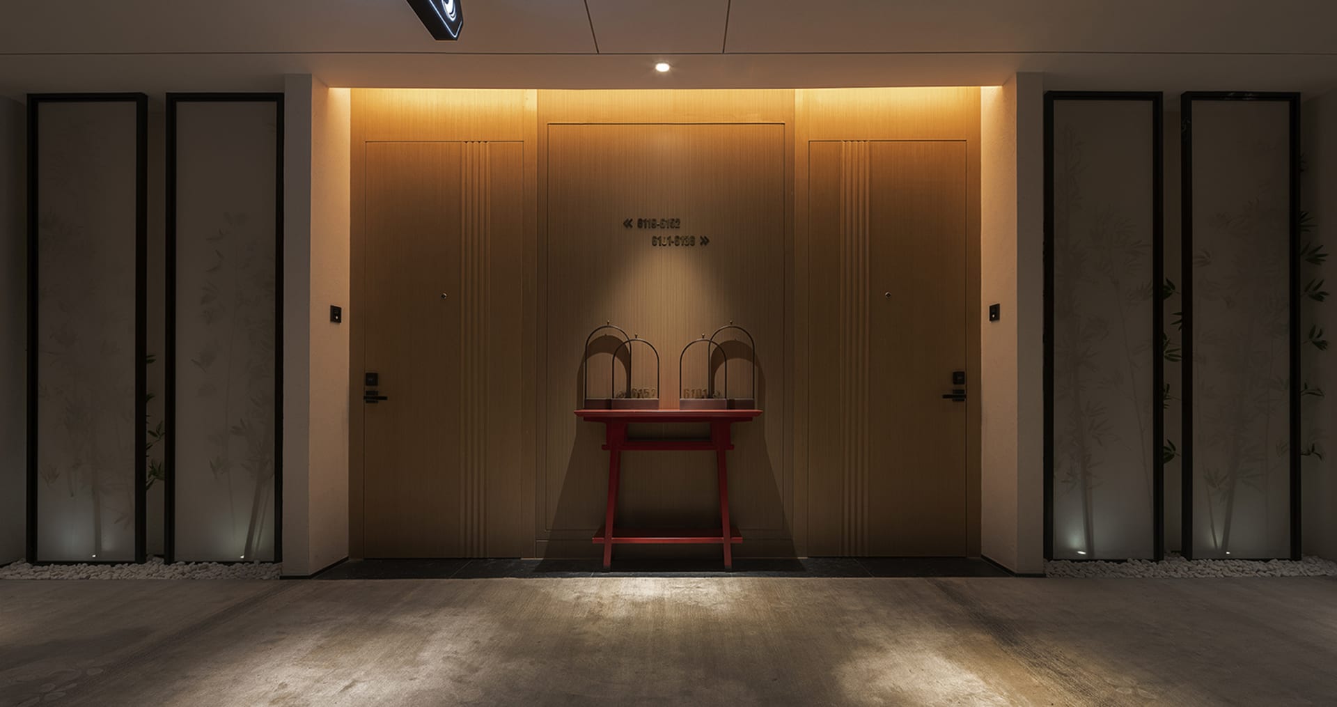 Modern minimalist entrance with wooden doors and a red table with baskets.
