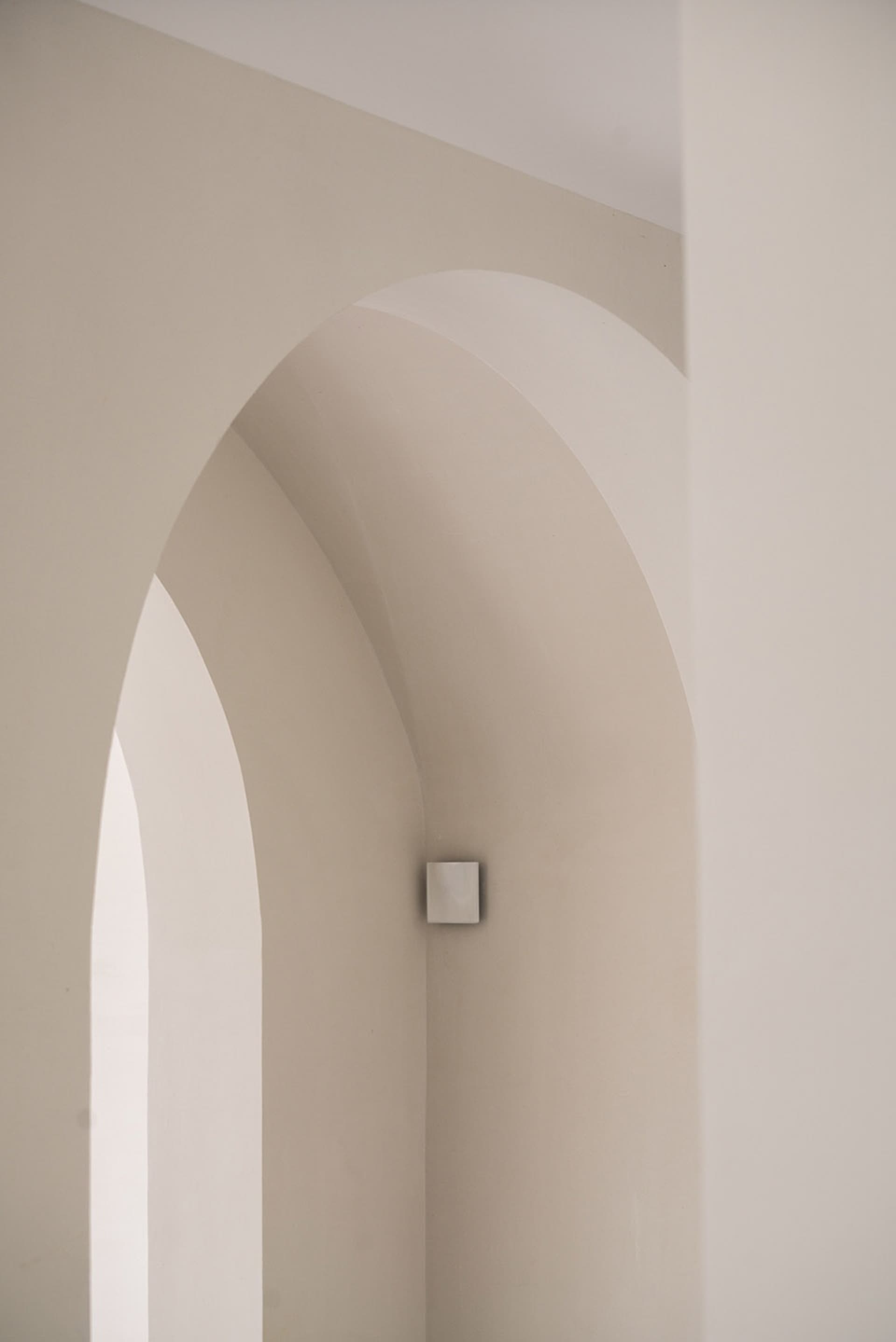A photograph of an architectural interior with concrete archways and minimalist design elements.