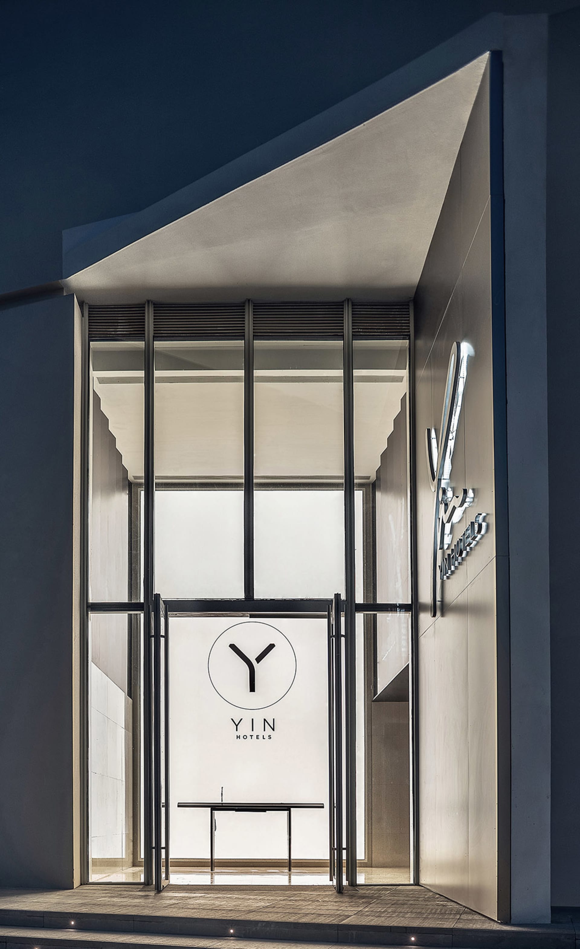 Modern hotel entrance with a glass door and metallic frame.