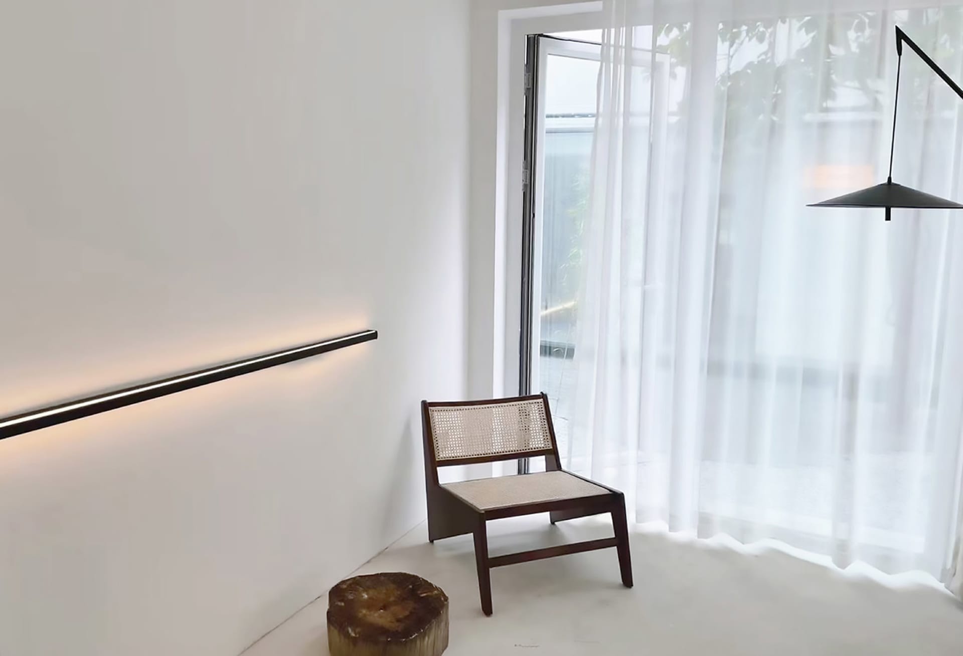 A minimalist interior featuring a large glass window and wooden furniture.