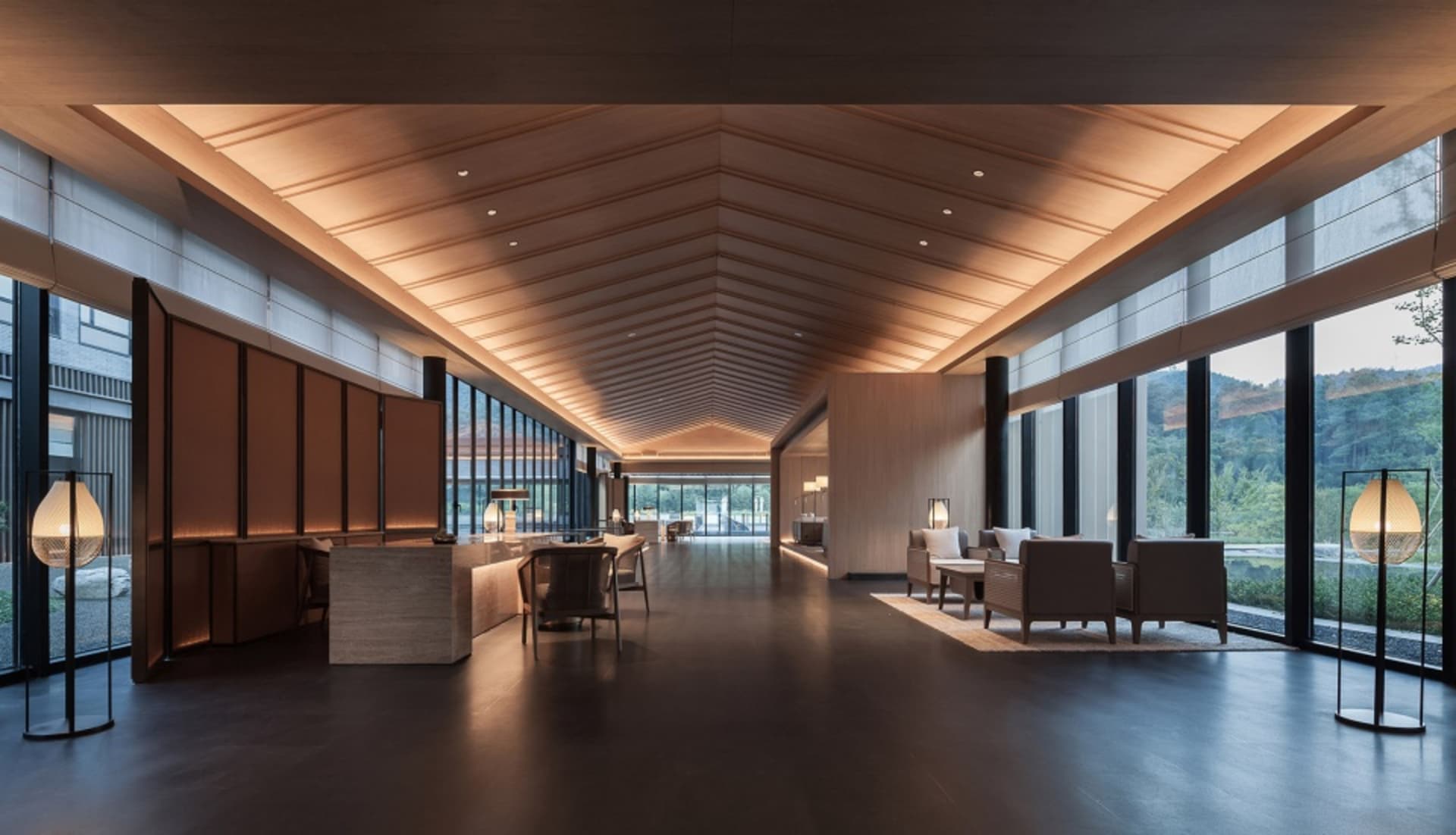 Modern hotel lobby with wood paneling, glass windows, and concrete flooring