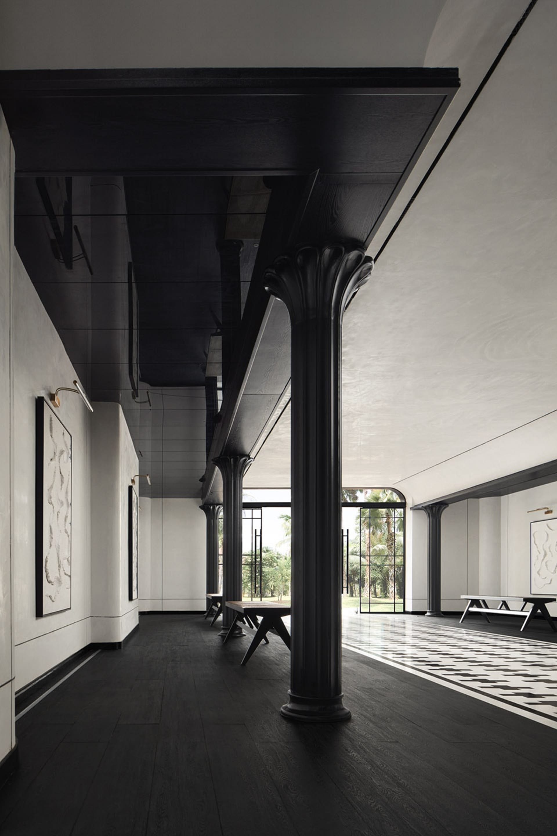 Modern interior design featuring a corridor with black wooden floors and ceiling, arches, and white walls with framed artwork