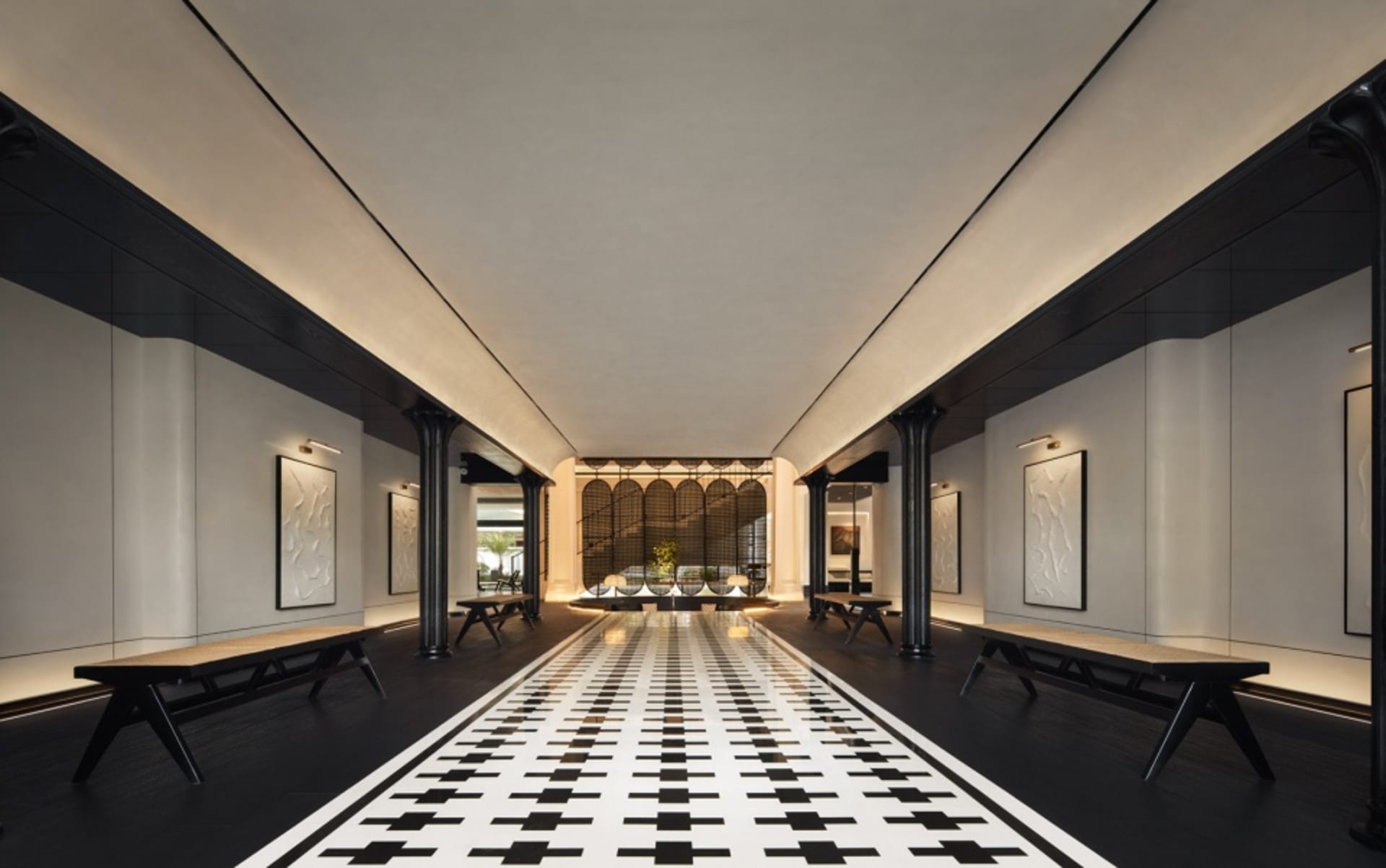 A modern hotel lobby with concrete walls, black sand floor tiles, and a long black and white checkered floor leading to a sea