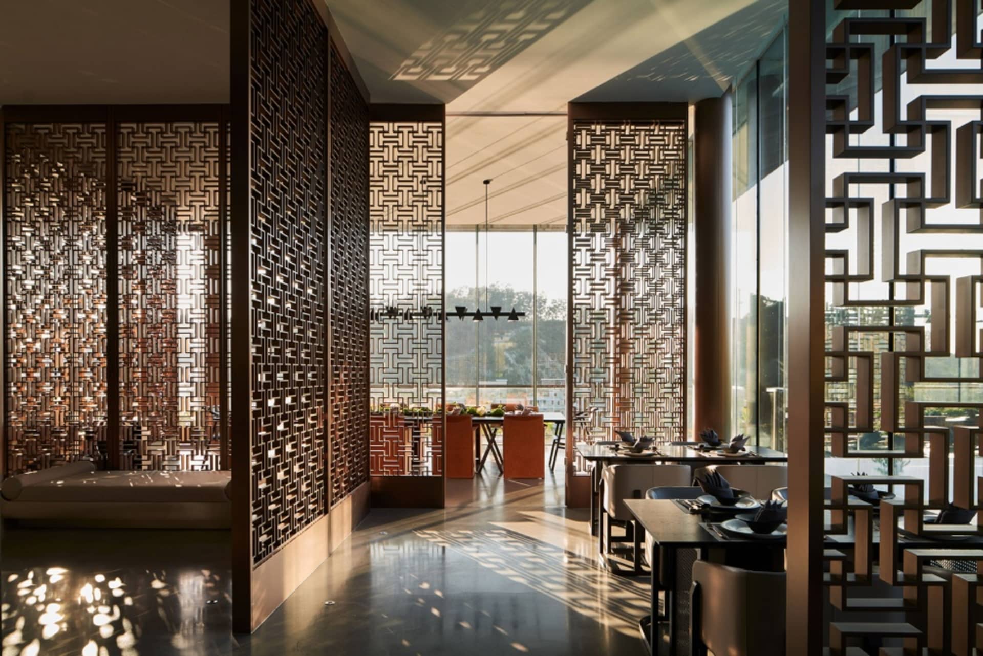 A modern restaurant interior featuring metallic wall screens and wooden tables.
