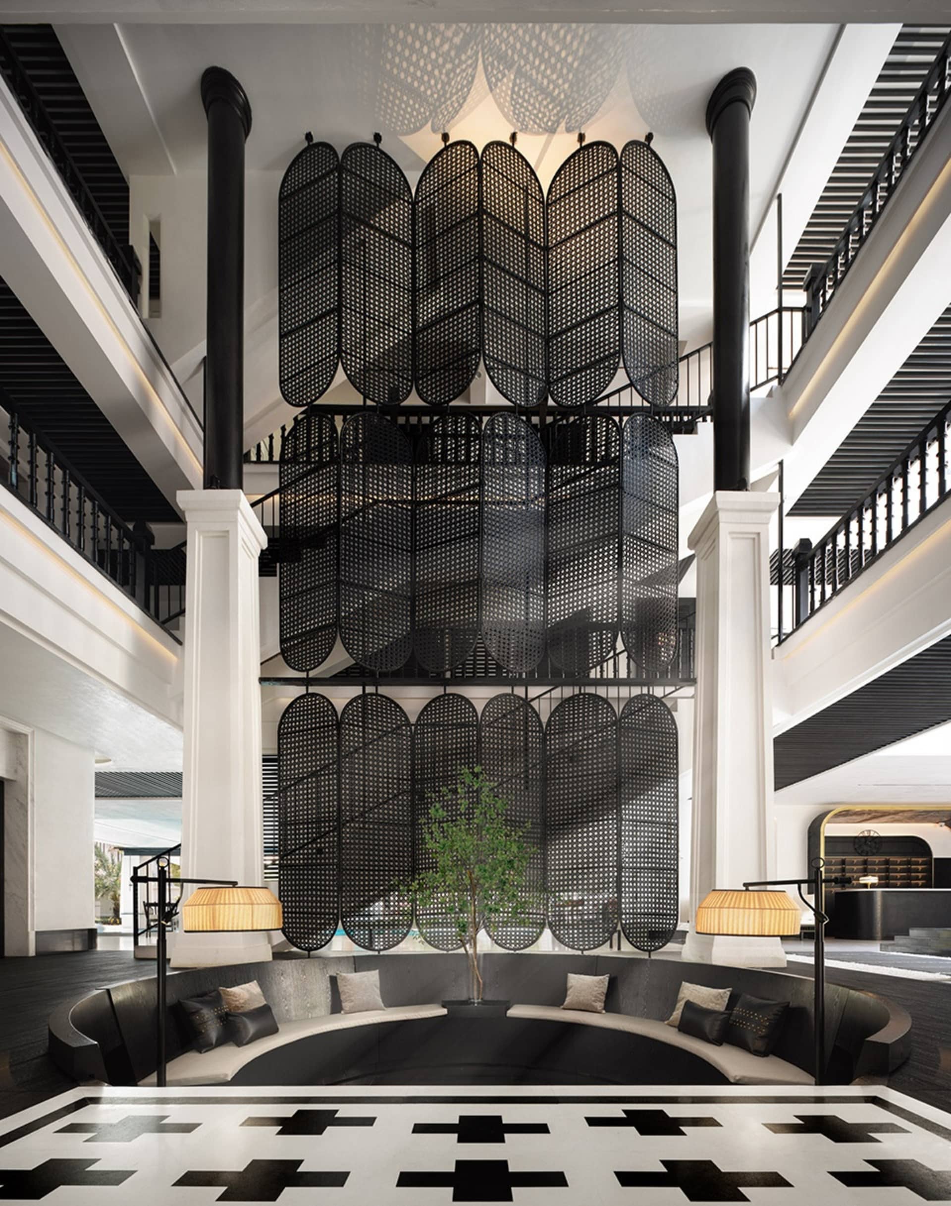 A modern hotel lobby featuring a black metal and wood design with a large planter and seating area.