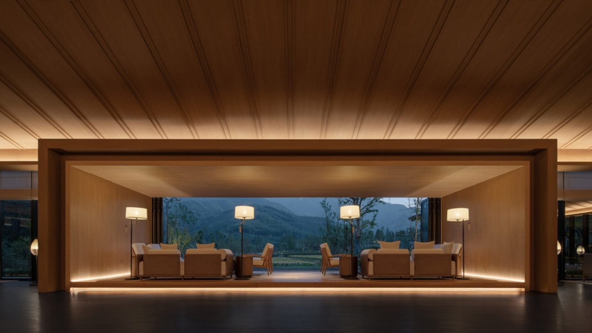 A minimalist lobby with wooden panels and floor-to-ceiling windows offering a view of the mountains.