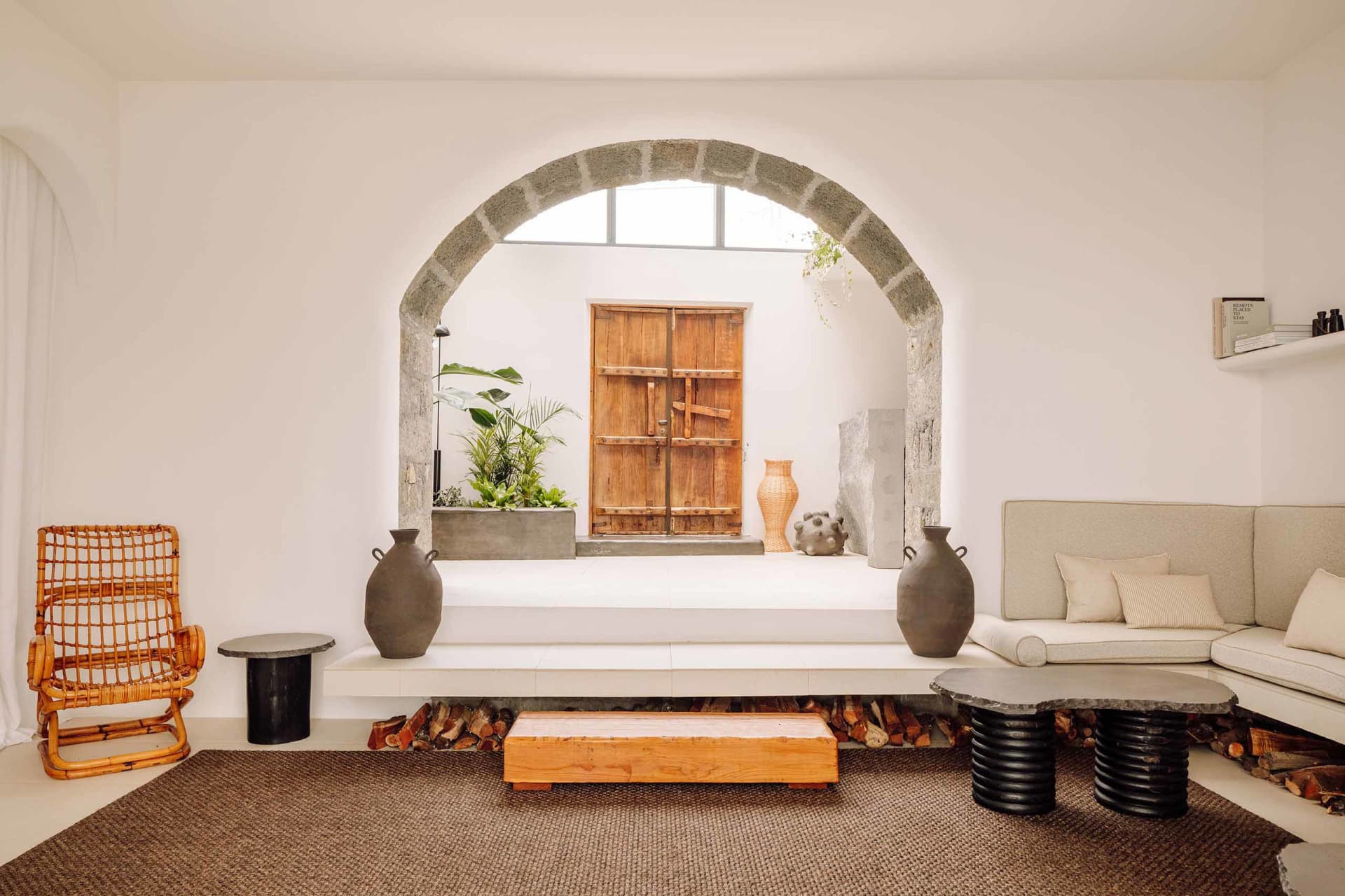 Modern minimalist living room featuring concrete walls, a white sofa, and rustic wooden furniture.