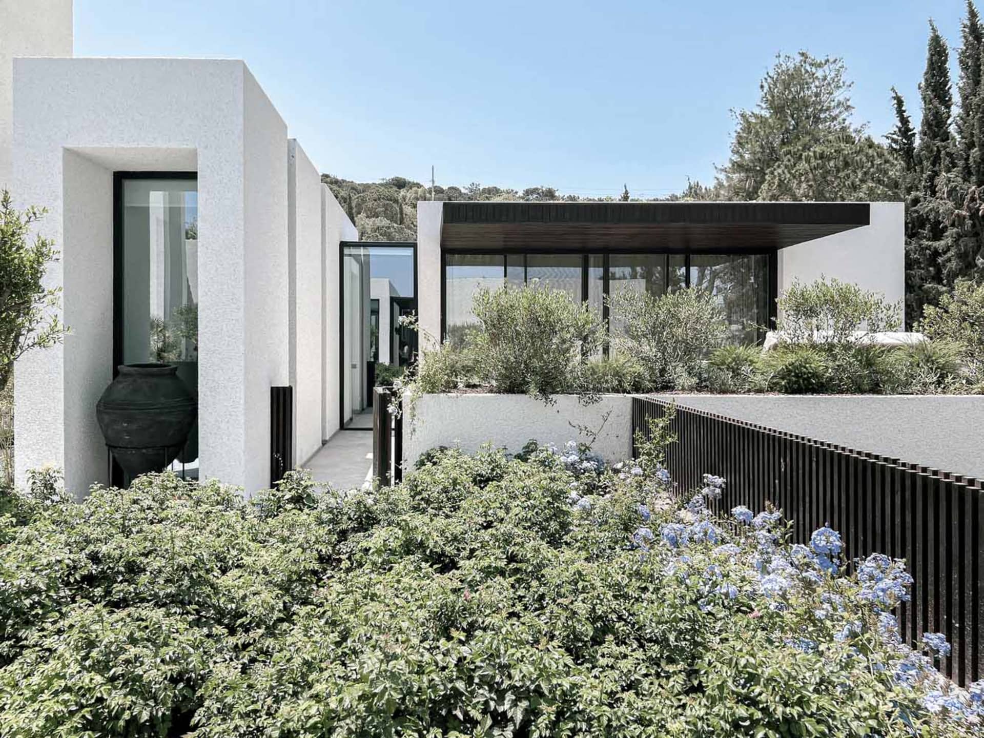 Modern residential home with white concrete exterior and large glass windows.