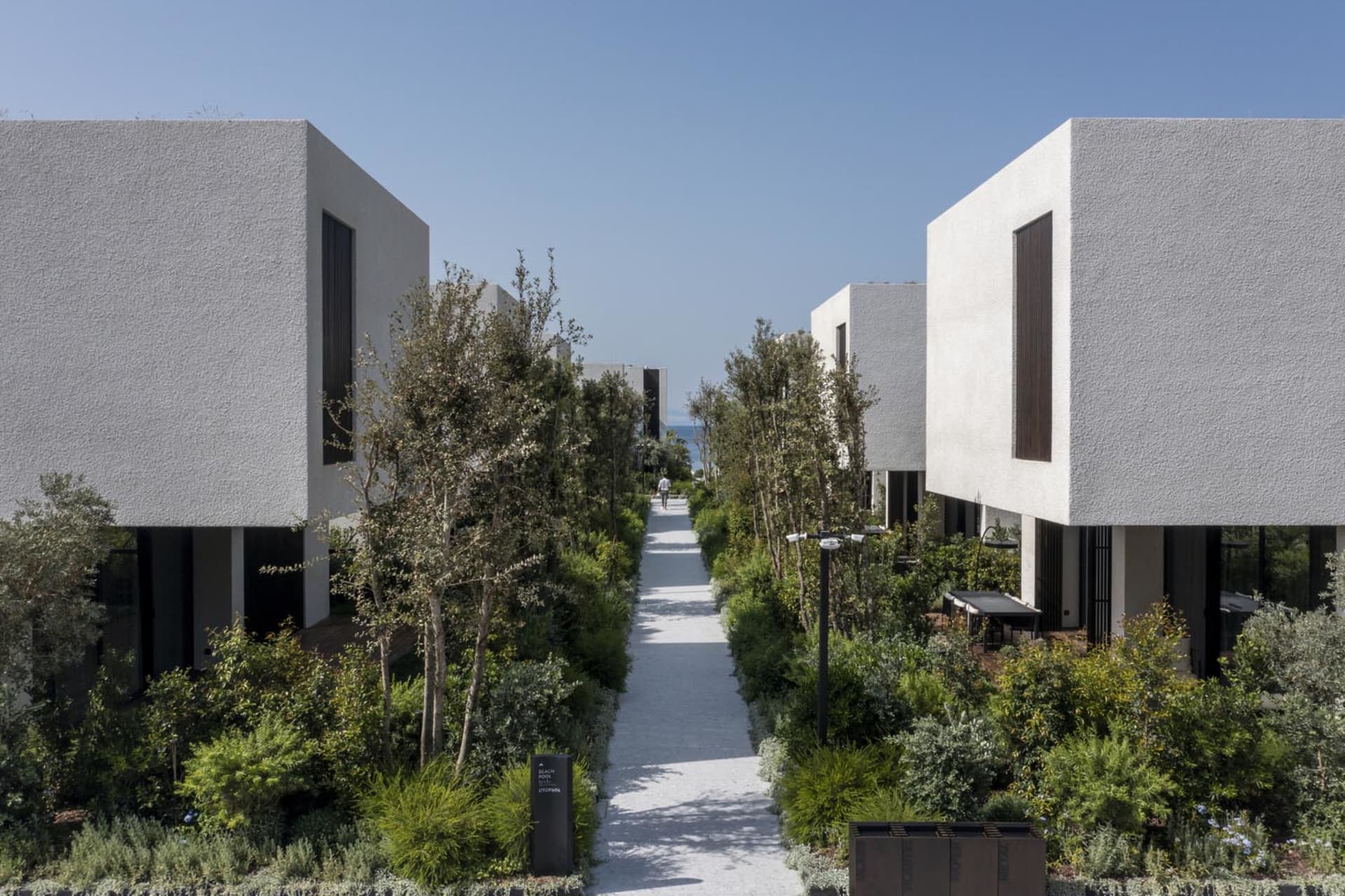 Modern house with concrete walls, glass windows, and stone pathways.