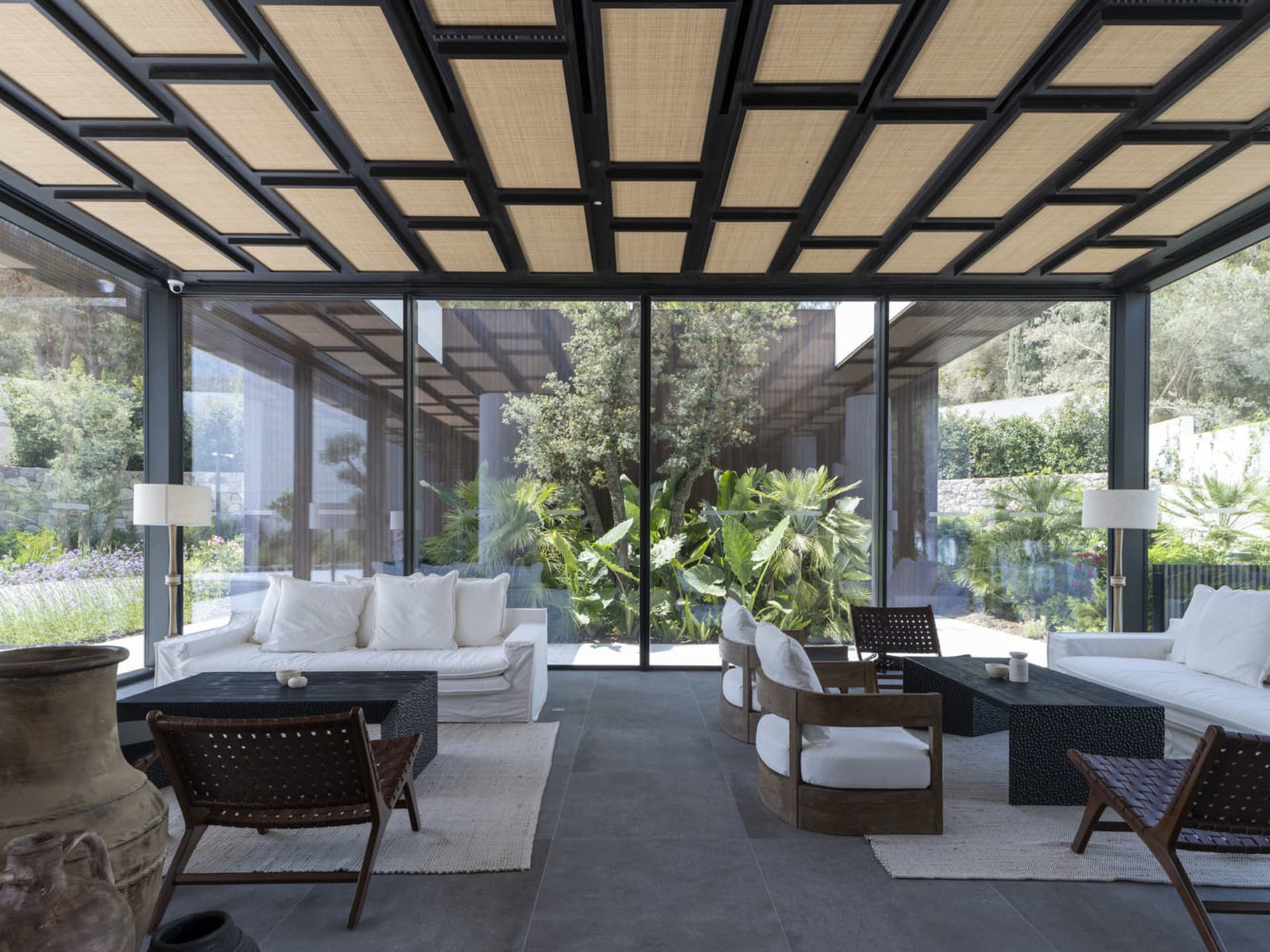 A modern living room featuring glass walls and a ceiling with geometric patterns.