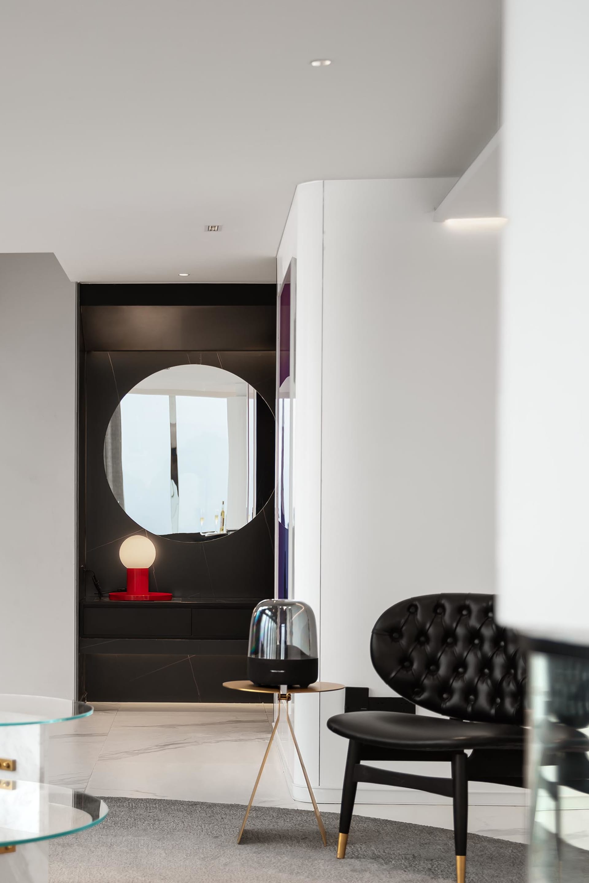 Modern minimalist living room with black marble and white marble accents and a sleek, black chair with golden legs.