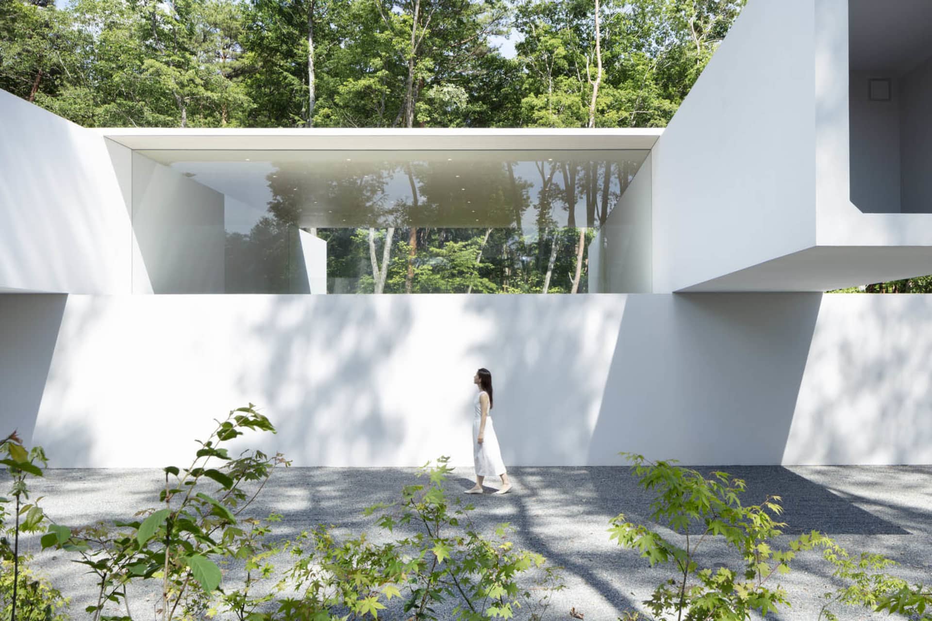 A modern building with white walls, glass walls, and concrete accents.