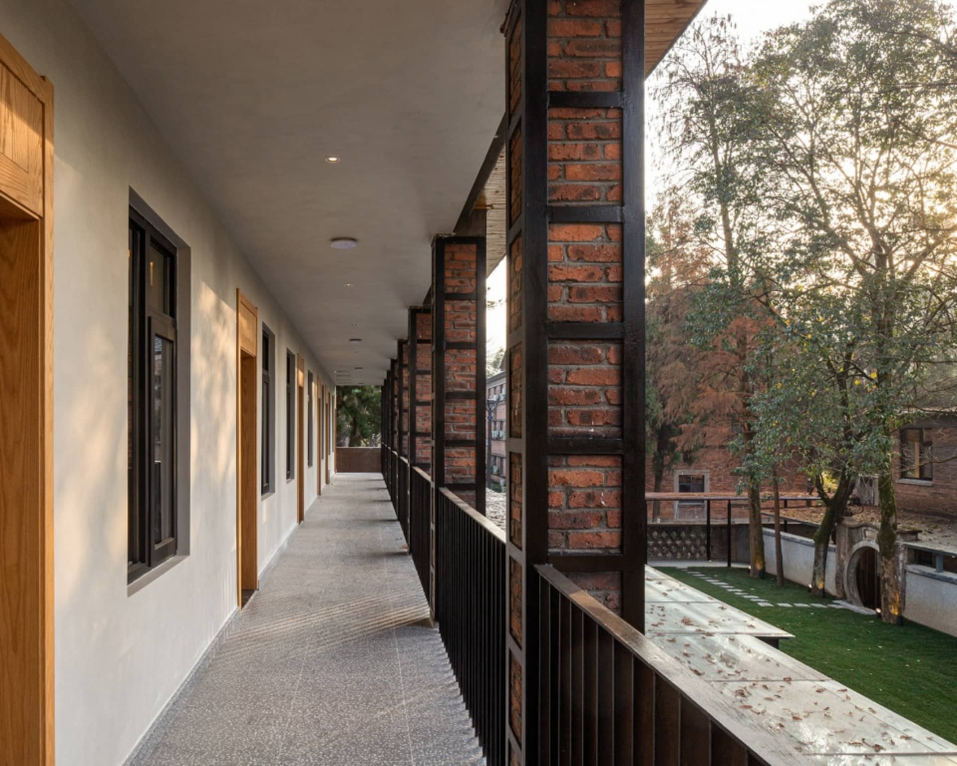 A modern corridor with brick and metal railings and doors.