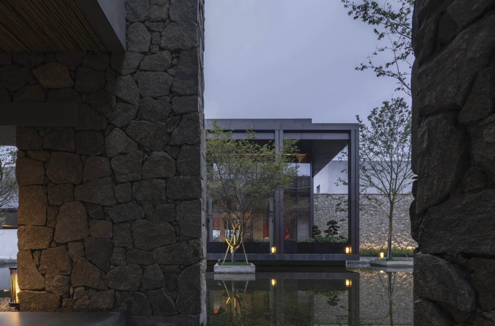 現代住宅外觀,擁有石牆、玻璃牆與景觀花園。