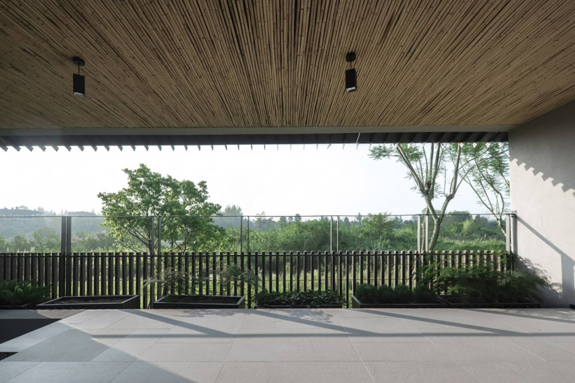 寬敞的現代住宅陽台，設有竹製天花板、玻璃隔板與瓷磚地板。