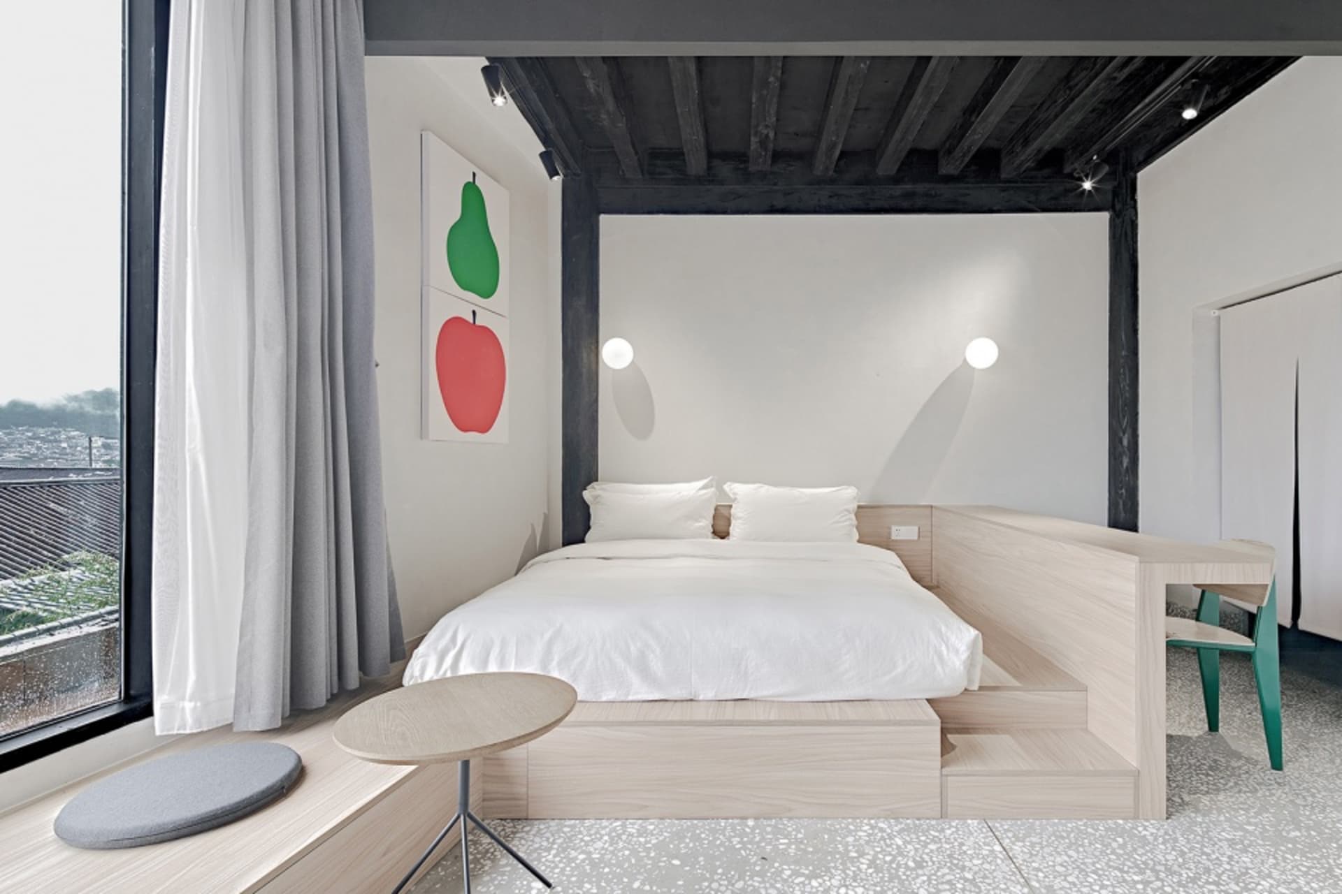 A minimalist bedroom with a bed on a raised platform made of white terrazzo and wood