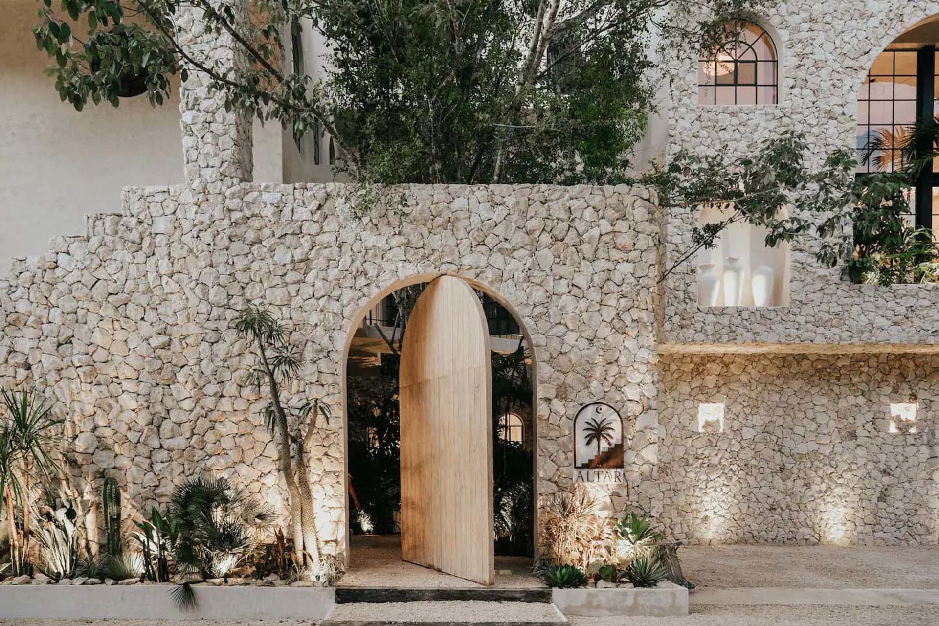 A modern residential entryway featuring a stone wall and wooden gate.