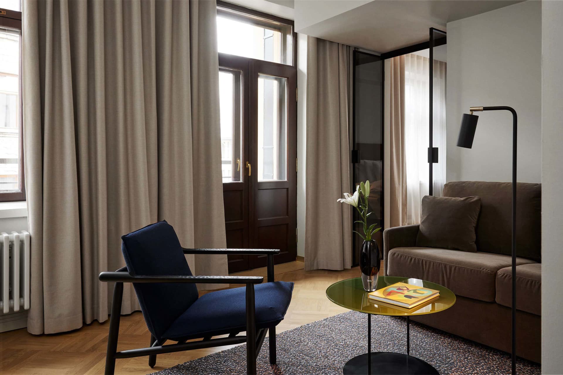 Modern living room featuring furniture made of cloth and metal with a floral centerpiece and floor lamp.
