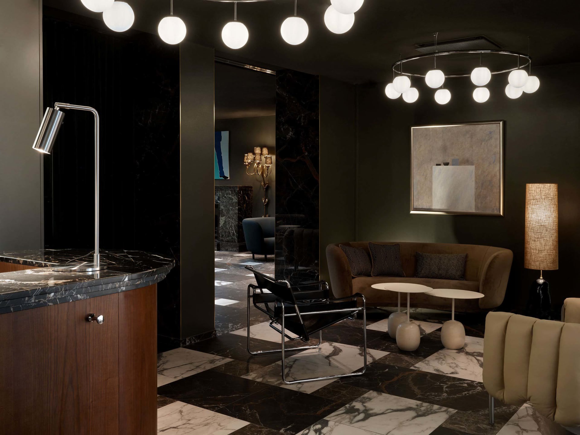 A modern living room with a marble floor, a beige sofa, and a black chair.