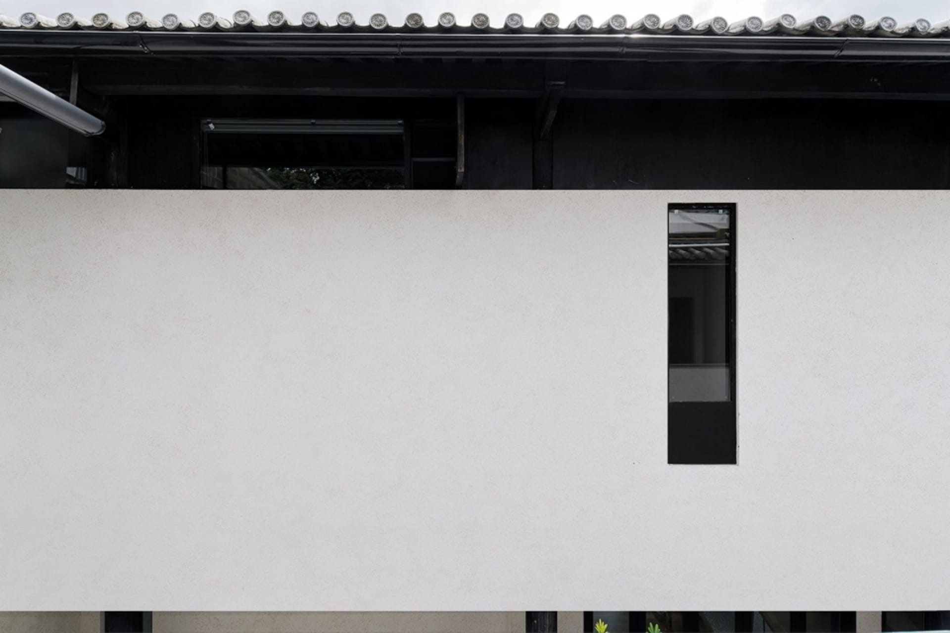 A modern residential building with a concrete exterior, minimalist design, and a unique geometric window.
