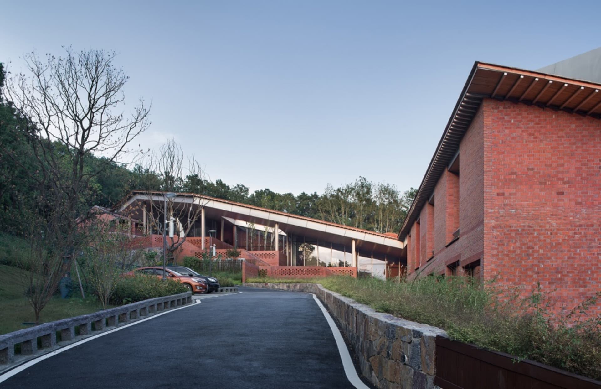 Modern brick building exterior with a sloping roof and stone pathways