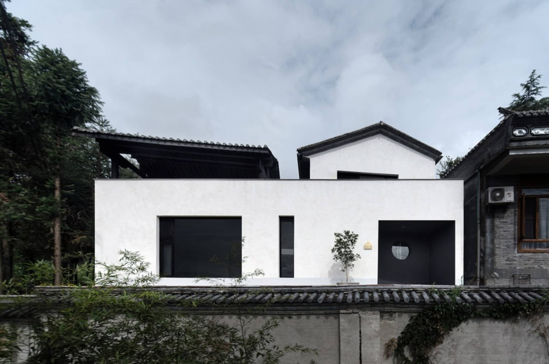 A modern house with a white exterior featuring glass windows and a flat roof.