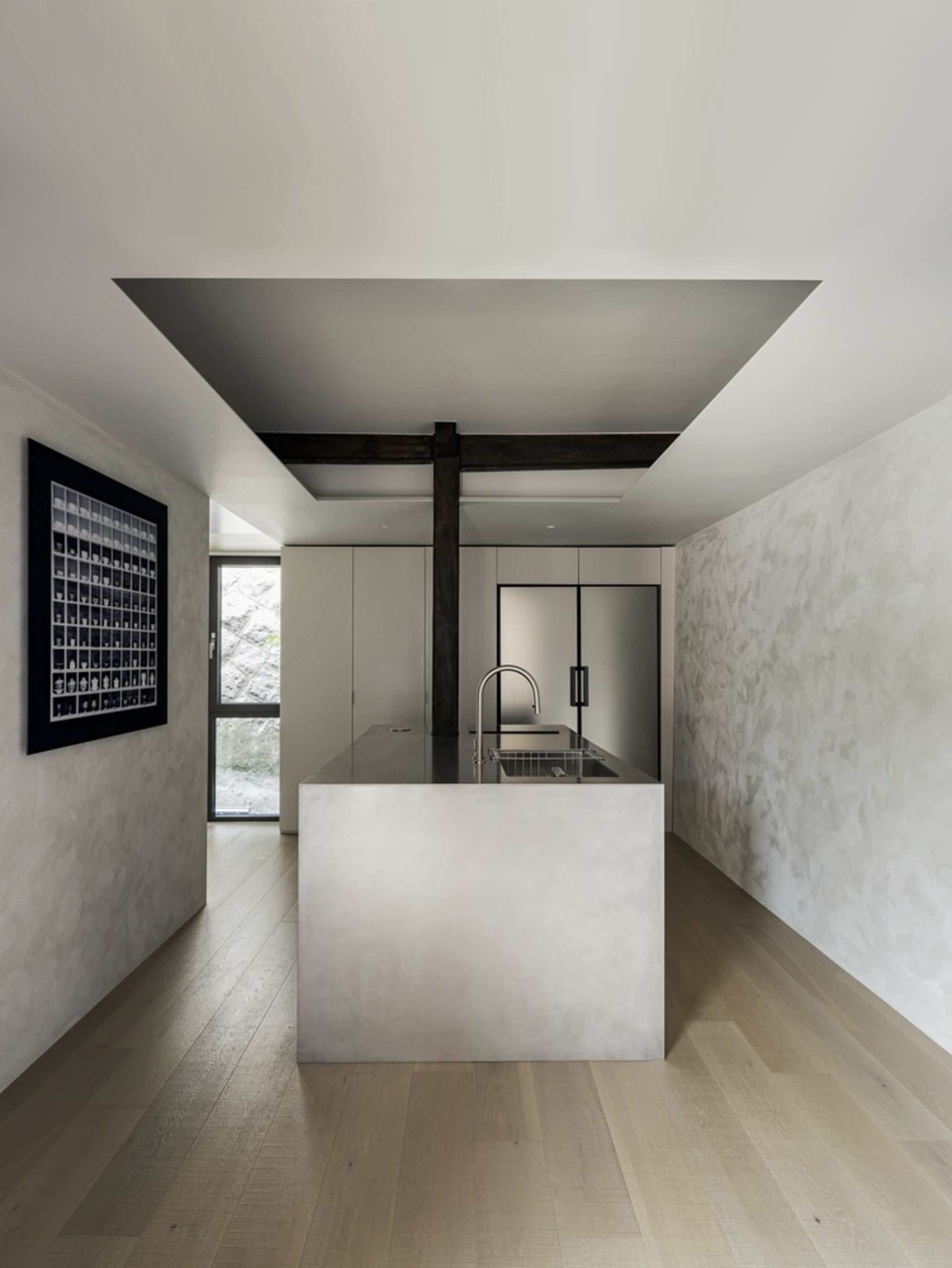 Modern kitchen with minimalist design featuring concrete countertops and stainless steel appliances.