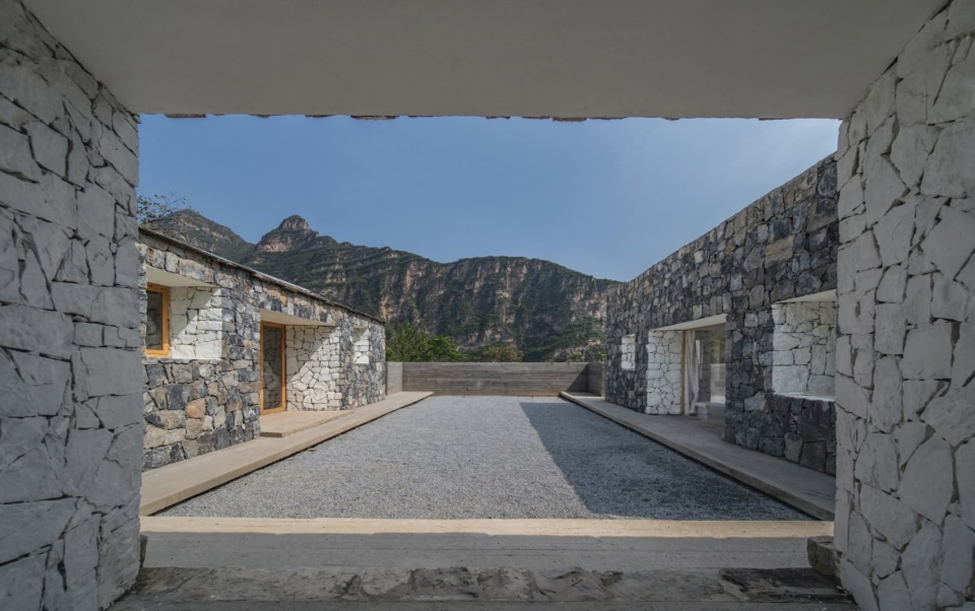 現代建築室內空間，融合石材外觀與山景中的中央花園。