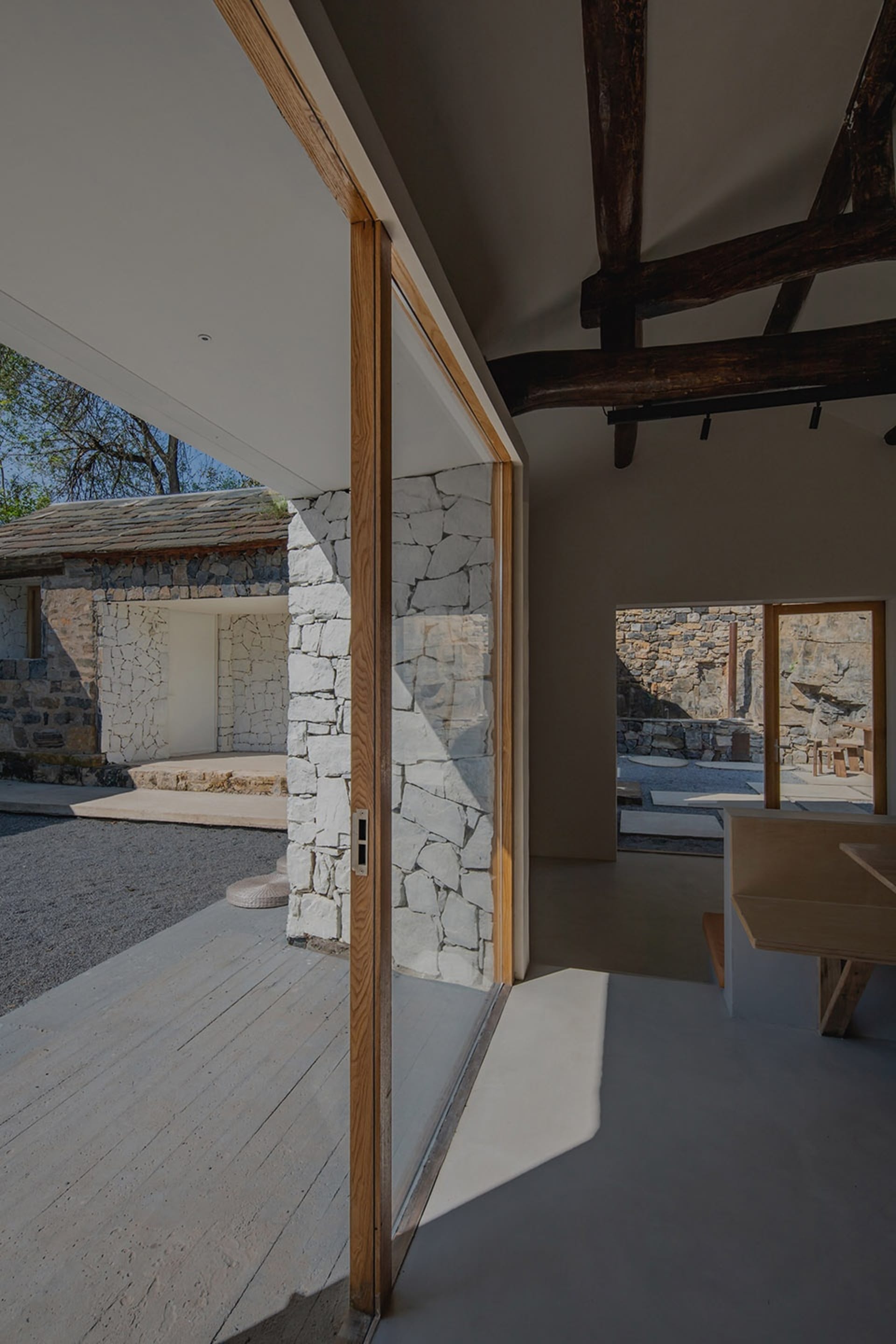 The image showcases a residential extension featuring stone walls, concrete flooring, and wooden beams.
