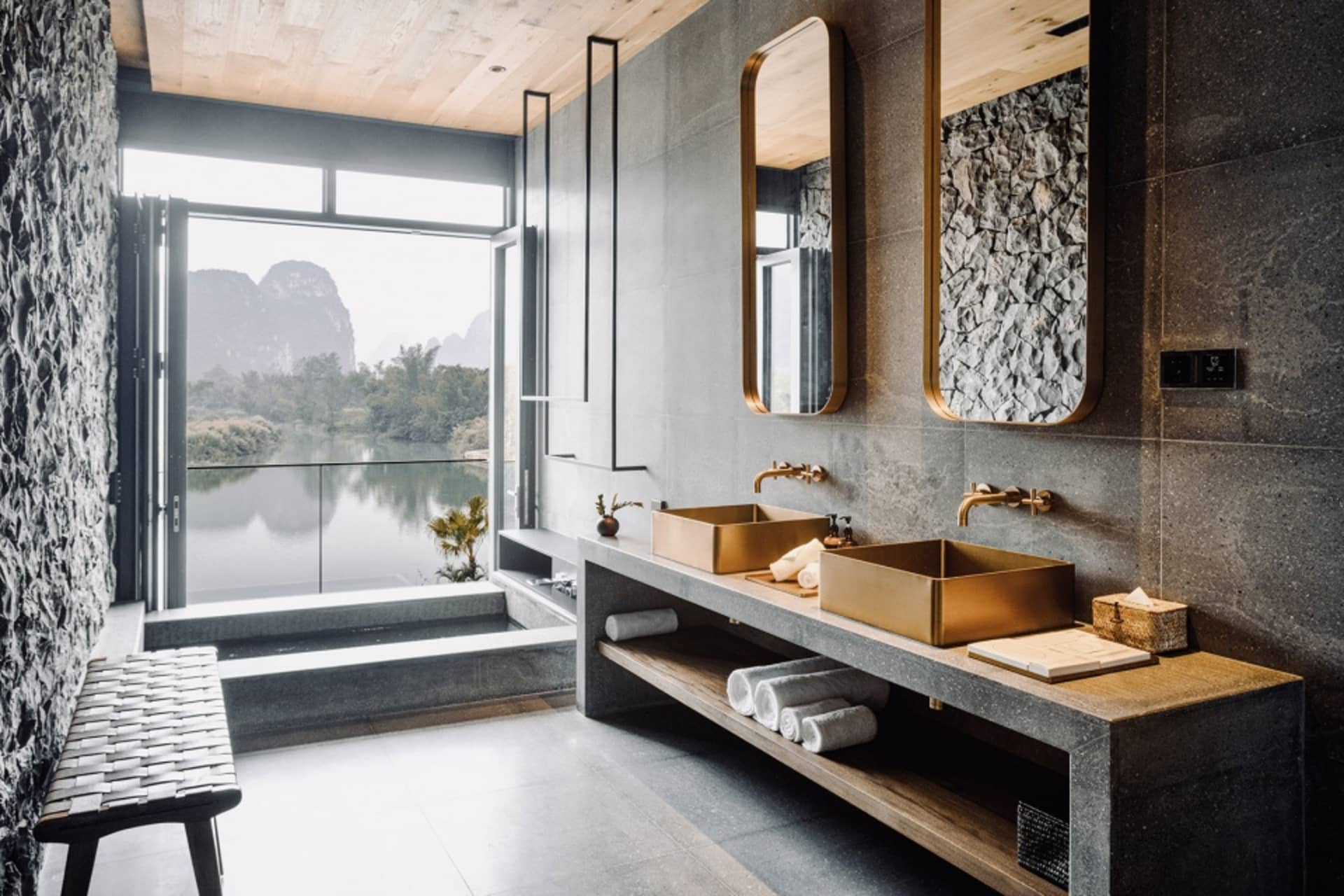Modern minimalist bathroom with concrete walls, wooden accents, and metal sinks.