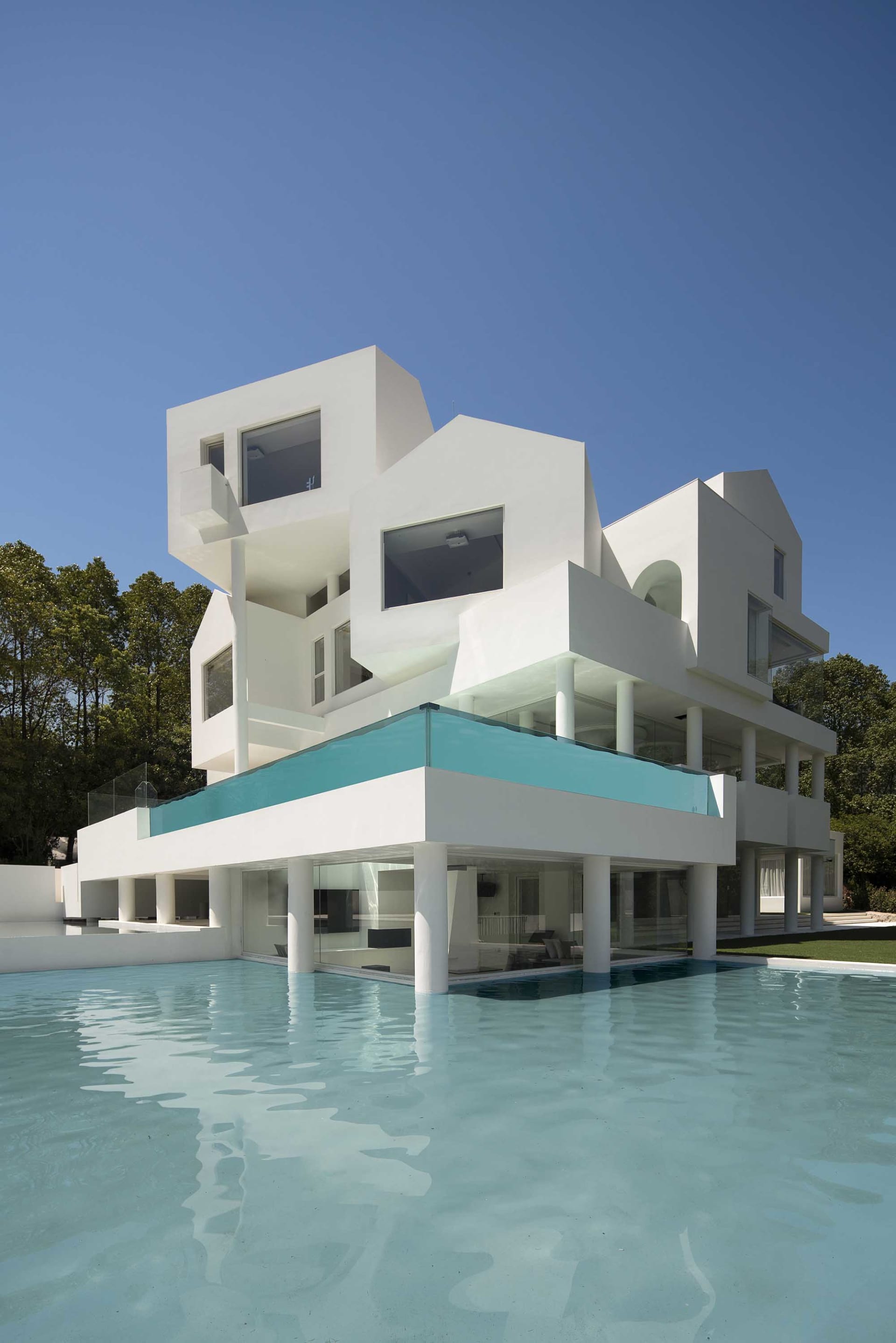 Contemporary residential building with minimalist design, primarily constructed from white concrete, glass, and steel.