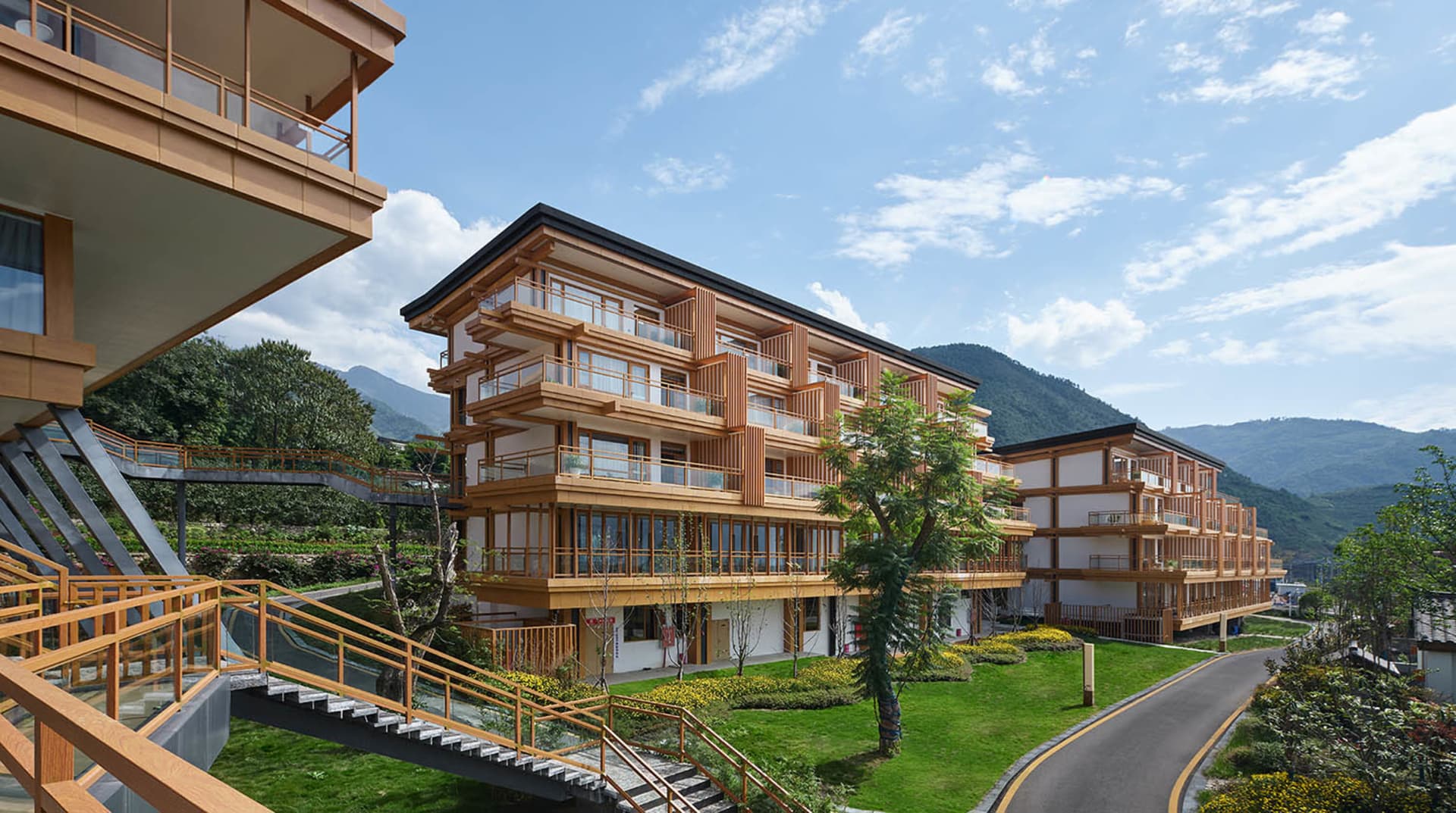 現代公寓建築採用木質框架外觀與陽台設計,背景為山景。