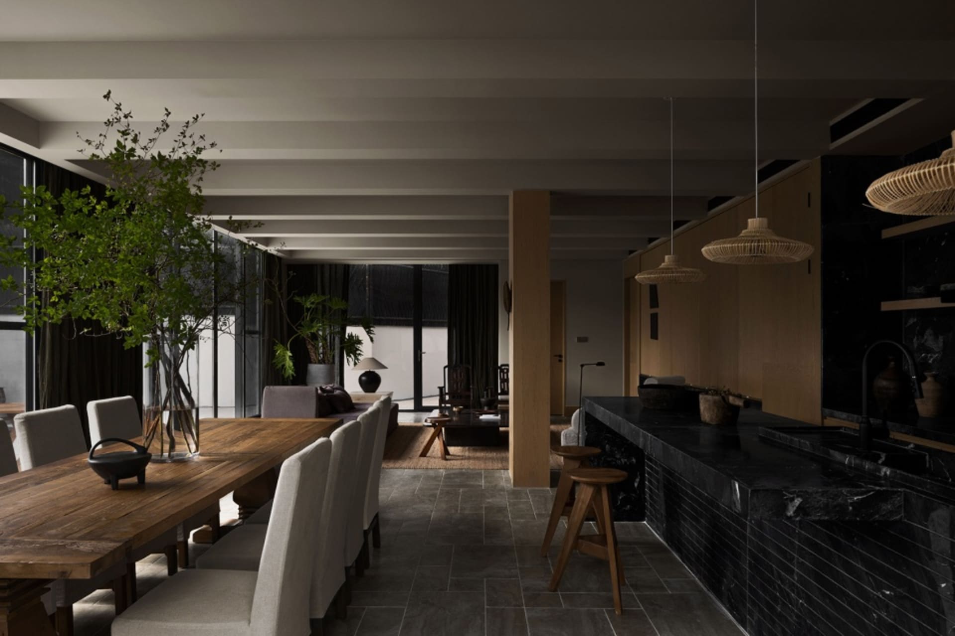 Modern dining area featuring a wooden table with upholstered chairs and a black marble kitchen counter.