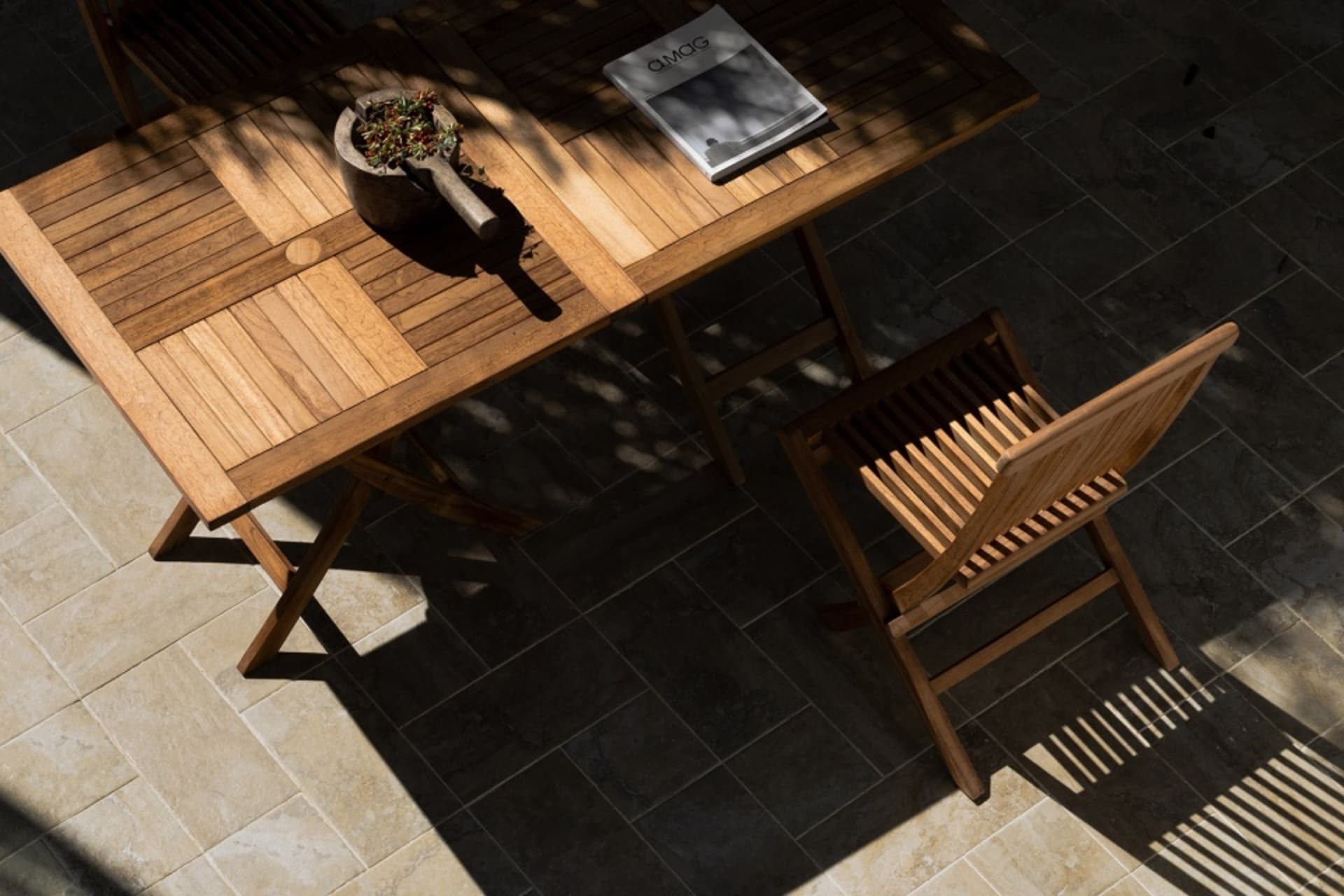 A wooden table and chair set with a magazine and a mortar and pestle.