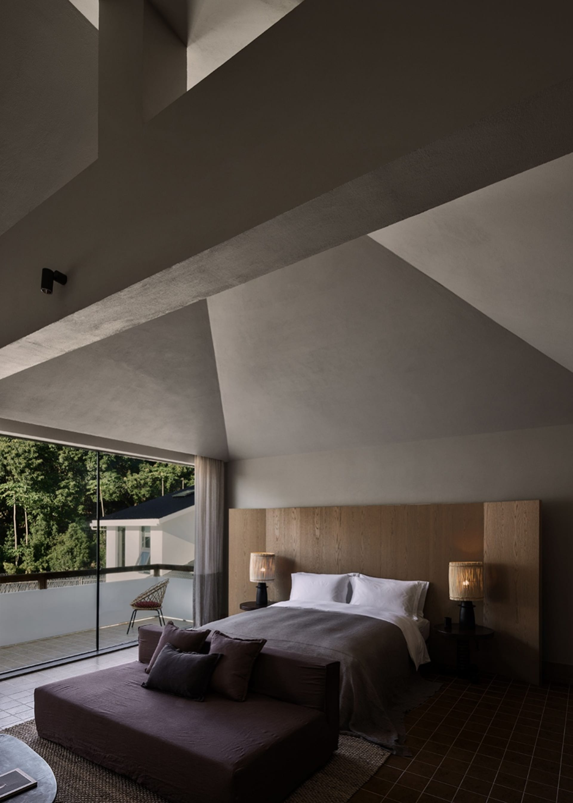 A modern bedroom with a concrete ceiling, wooden headboard, and fabric bedding.